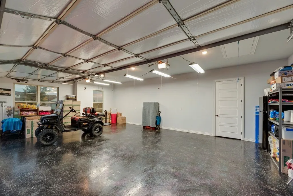 Spacious garage featuring a durable epoxy floor finish, multiple windows, recessed lighting, and a white paneled interior door