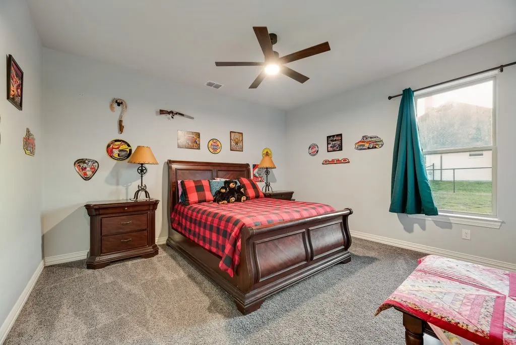 Carpeted bedroom featuring a window with exterior views, dark wood-finish furniture, a ceiling fan, and light-toned walls
