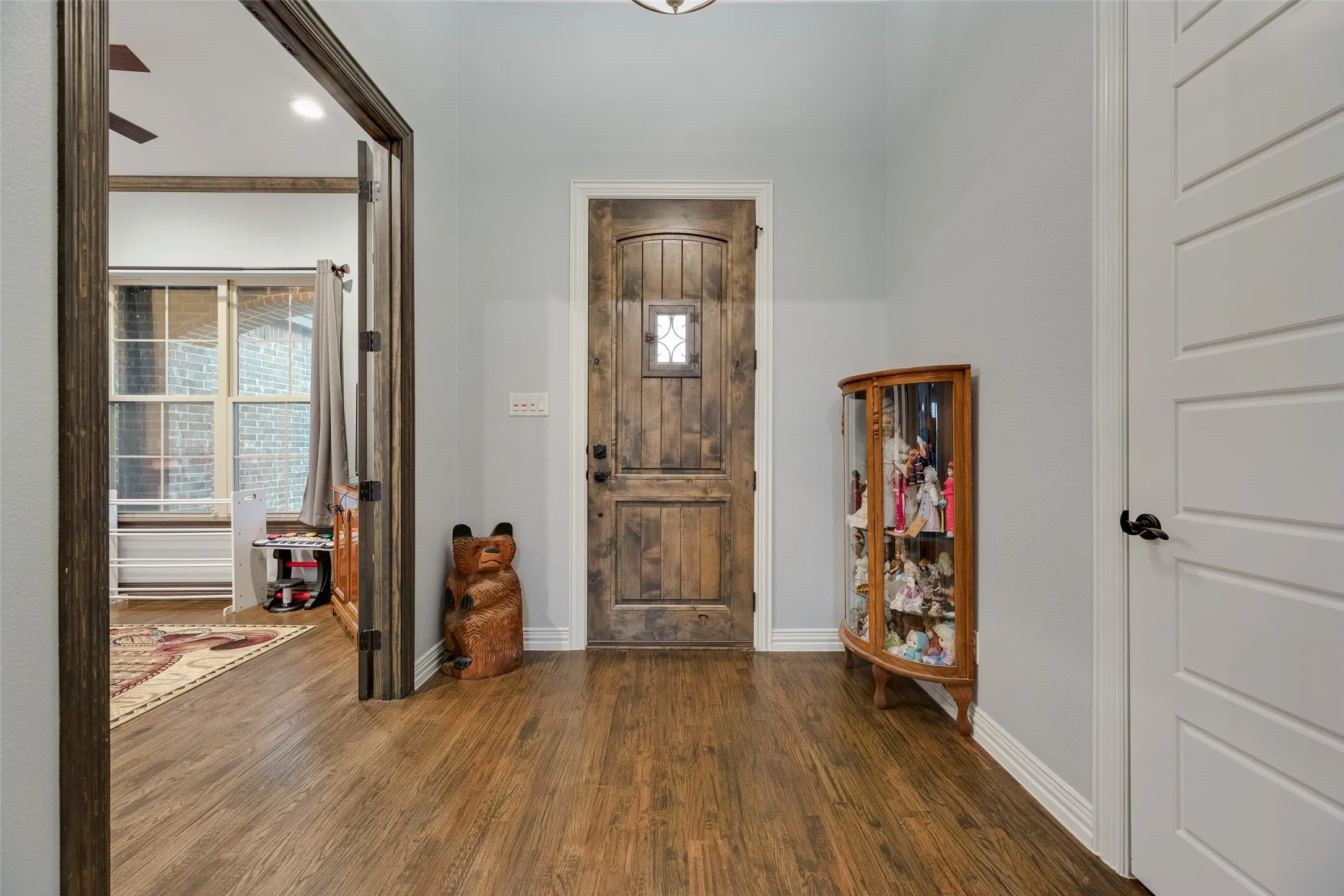 Distinguished entryway featuring a solid wood-panel door with decorative glass insert, wood-finish flooring, and crisp white baseboards