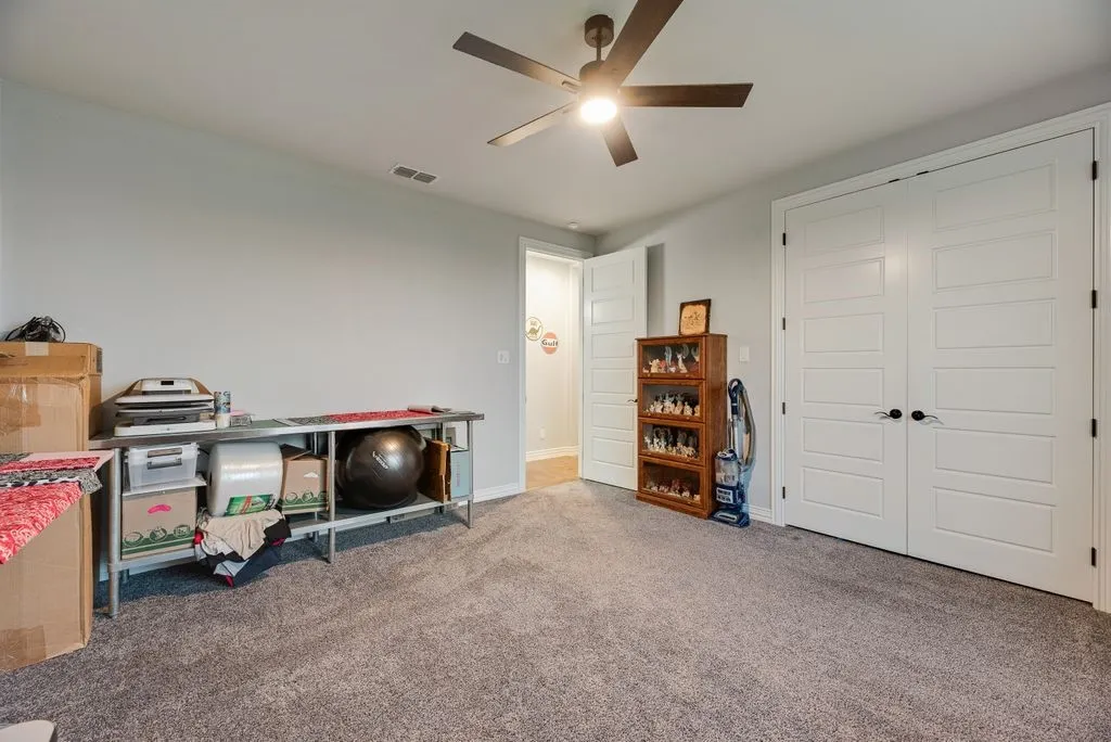 Carpeted room featuring a ceiling fan with integrated lighting, light gray wall paint, and white paneled doors with black hardware
