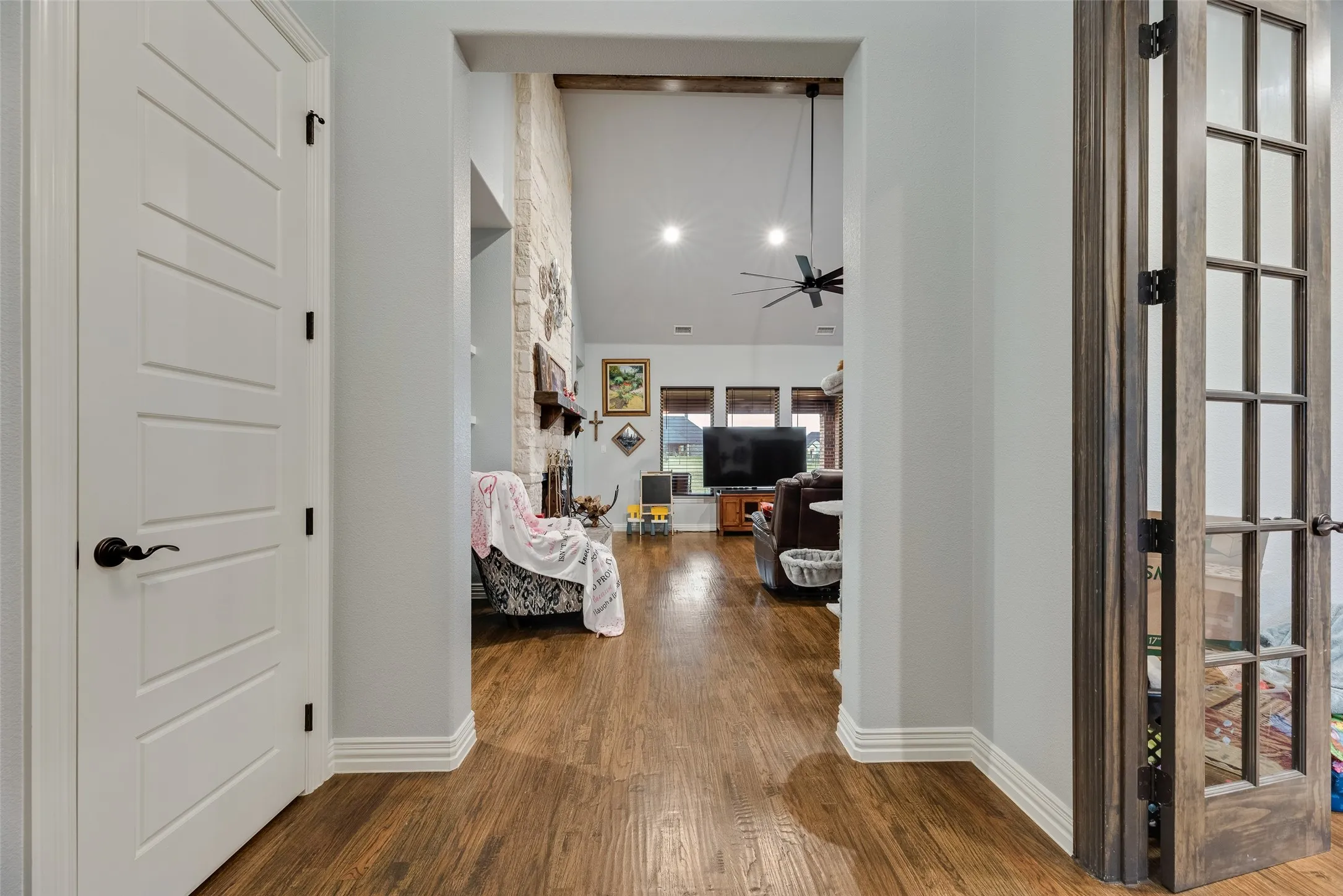 Hardwood-finish flooring extending through an arched entryway into an open living space
