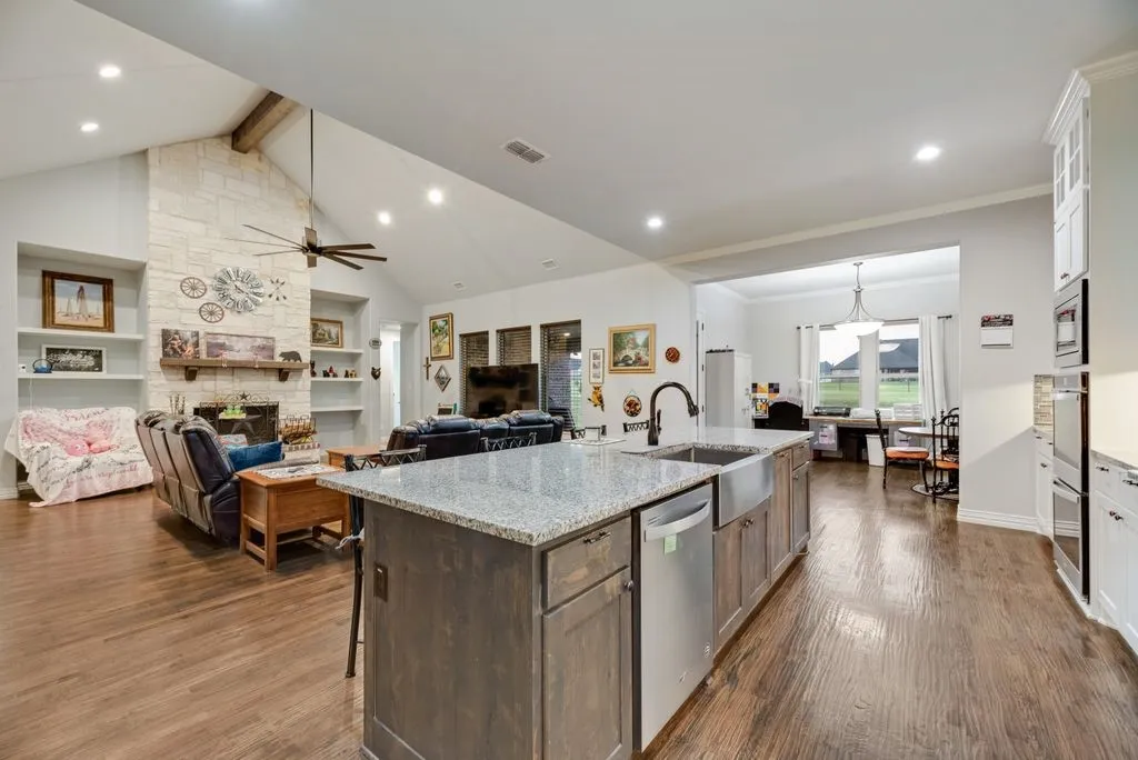 Expansive kitchen island with a stone-finish countertop, farm sink, and integrated dishwasher