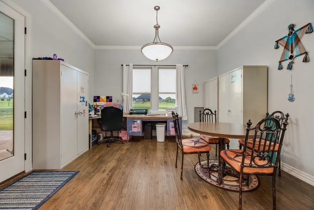 Spacious interior room featuring wood-finish flooring, light gray walls, and white crown molding