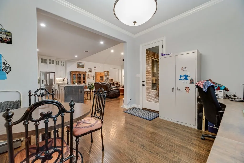 Hardwood-finish flooring extending into the living area, crown molding, and a full-light exterior door with a sidelight
