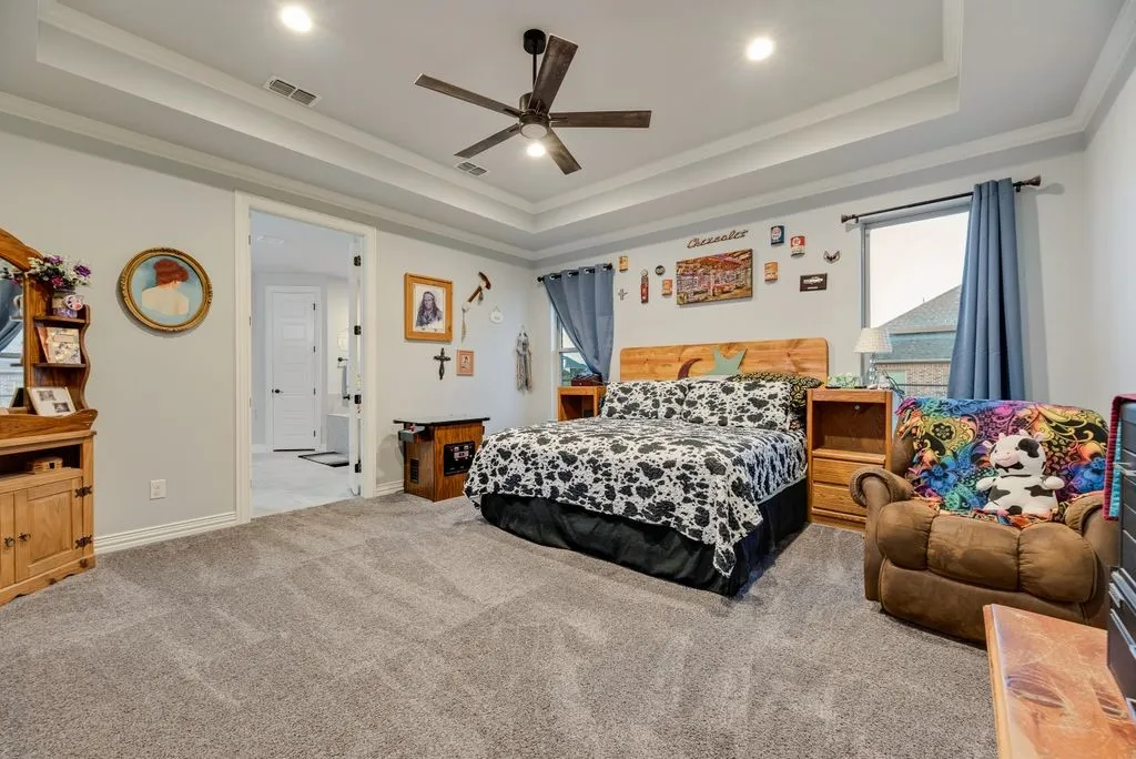 Spacious room featuring tray ceilings with recessed lighting, carpet flooring, and a ceiling fan