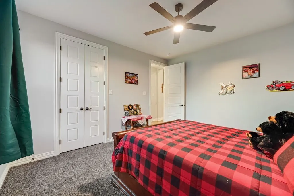 Carpeted room featuring a ceiling fan with integrated lighting, dual paneled closet doors, and light gray wall paint