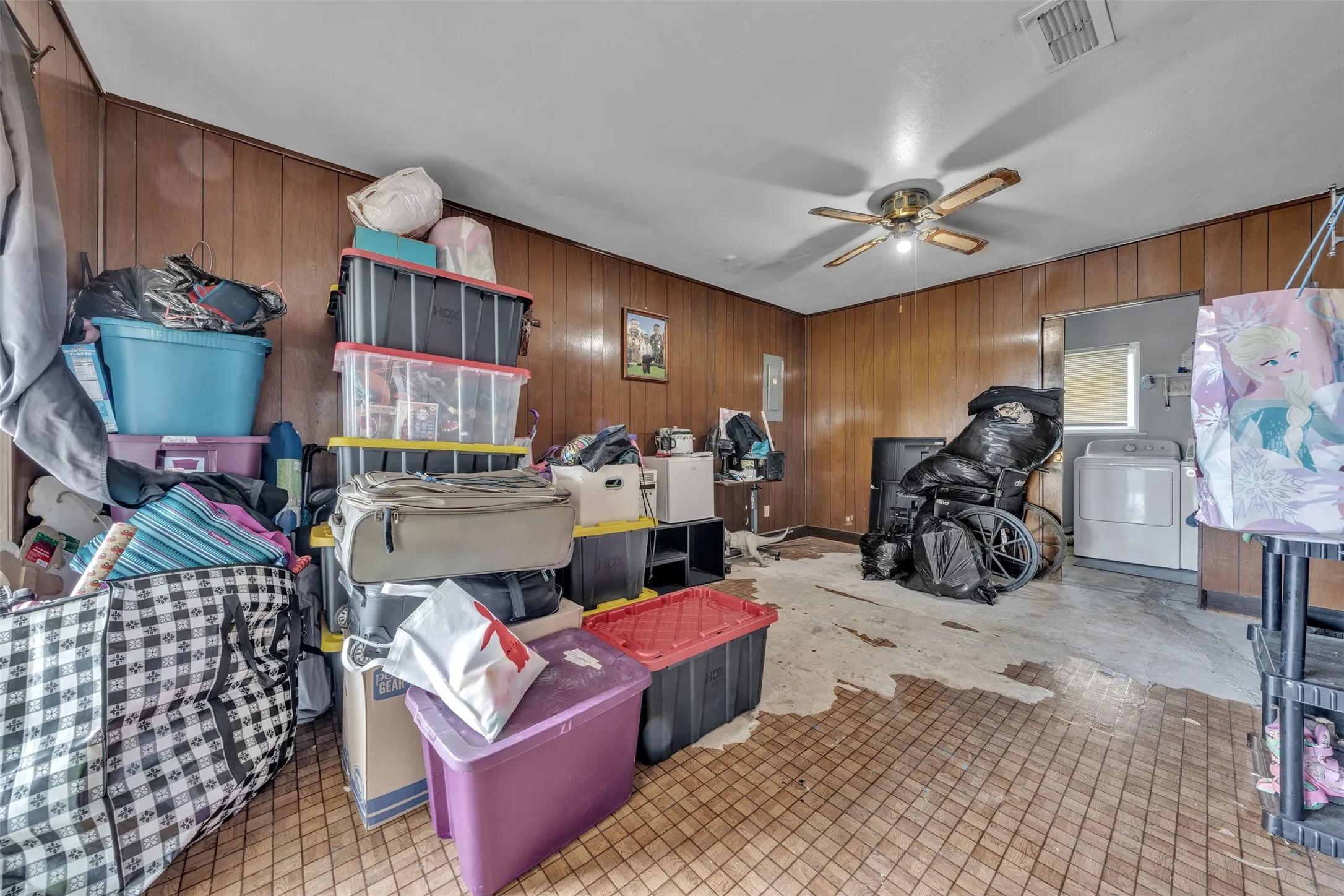 Utility space featuring wood paneling, a ceiling fan, and a pass-through window