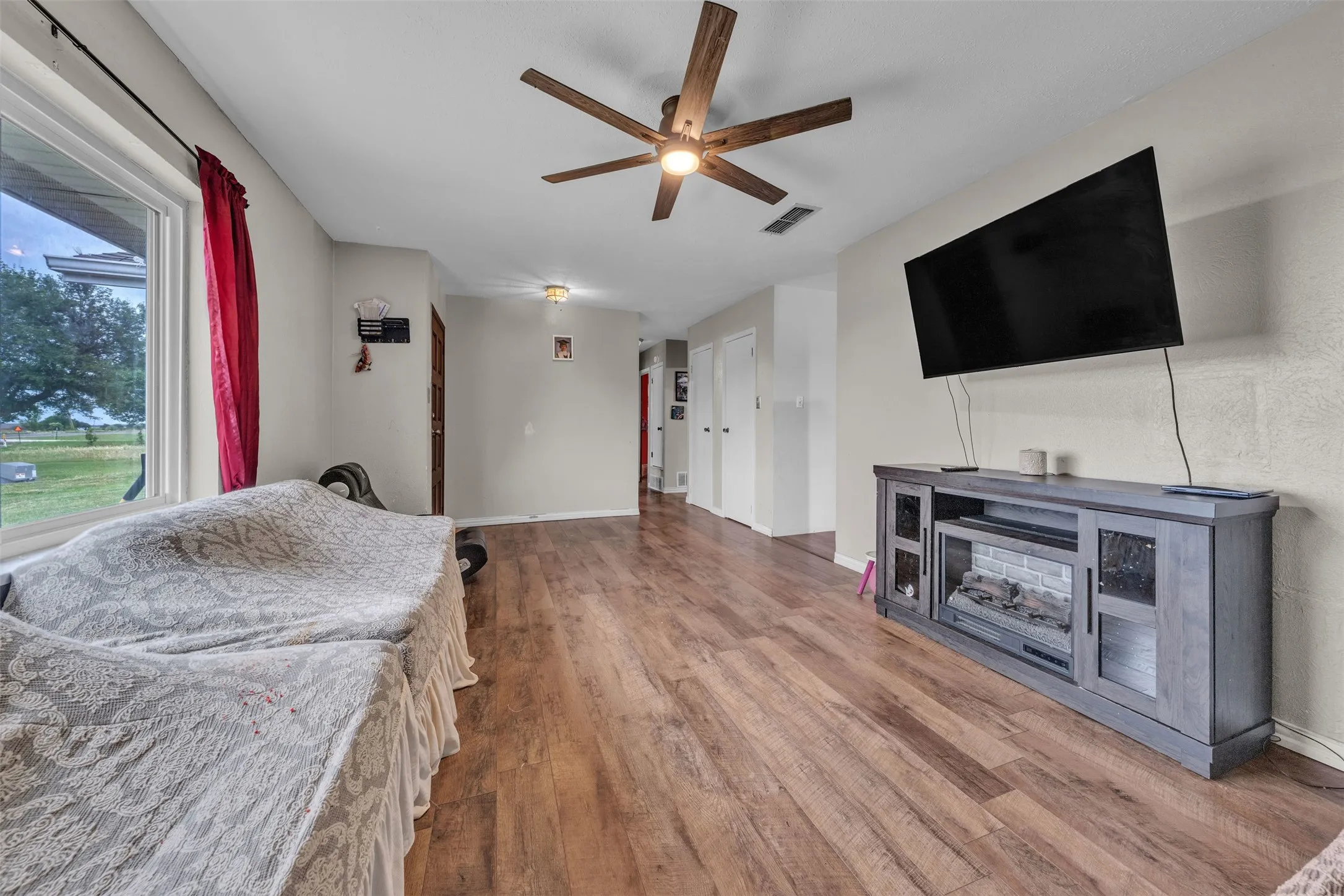 Spacious room featuring wood-finish flooring, a contemporary ceiling fan, and a large window offering exterior views