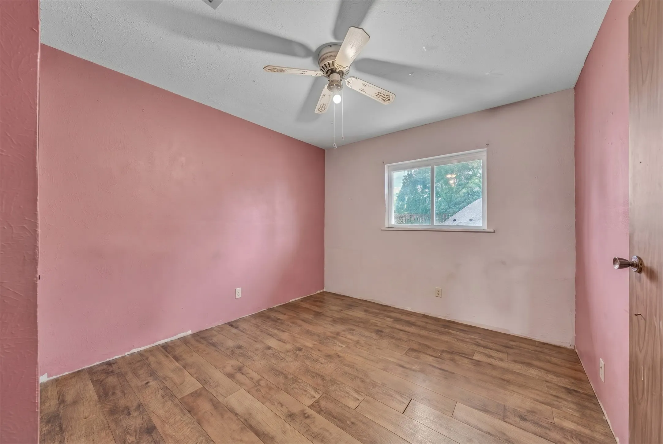 Interior room featuring wood-finish flooring, a ceiling fan with integrated lighting, and a single window