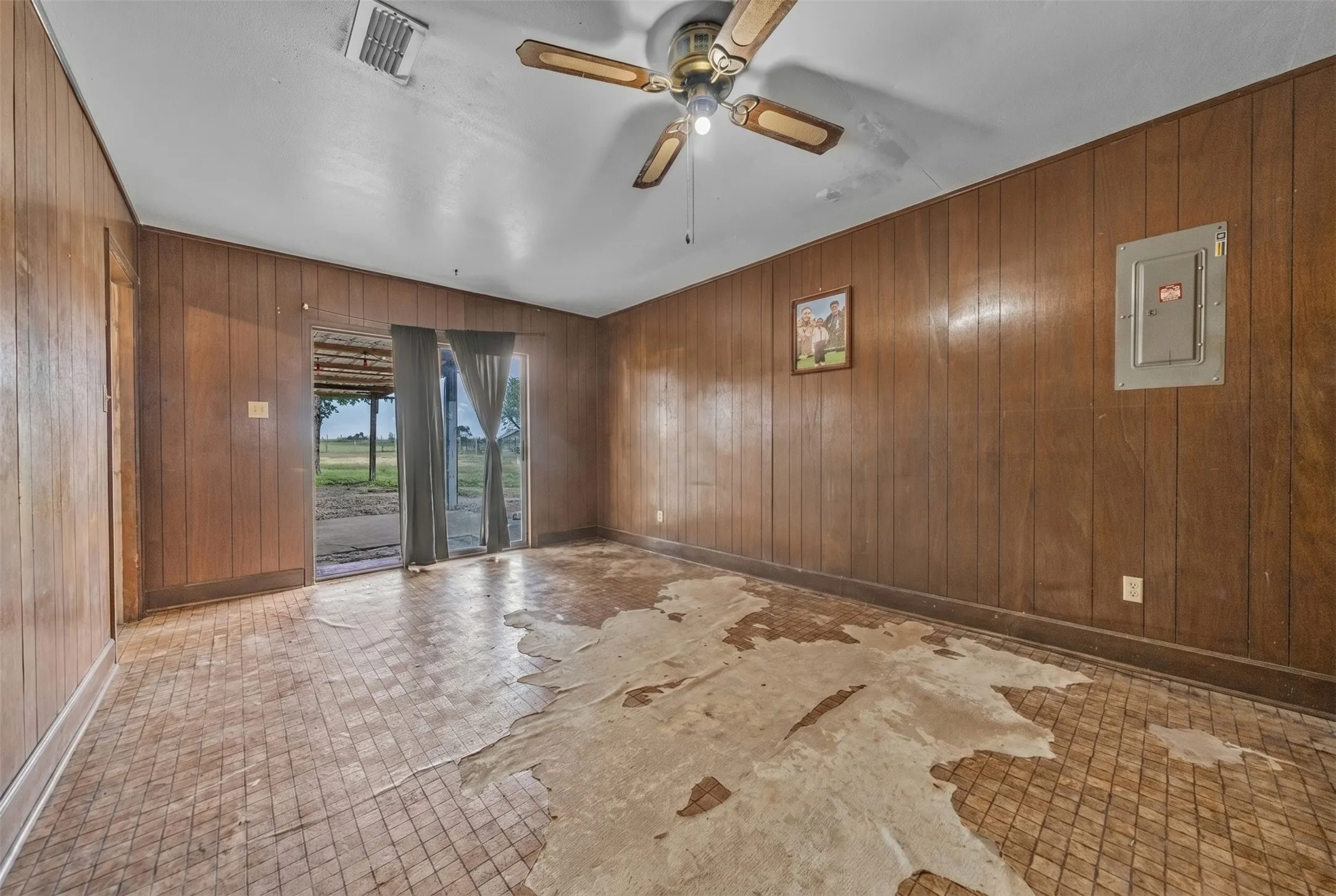 Interior space featuring wood-paneled walls and a white ceiling with a ceiling fan