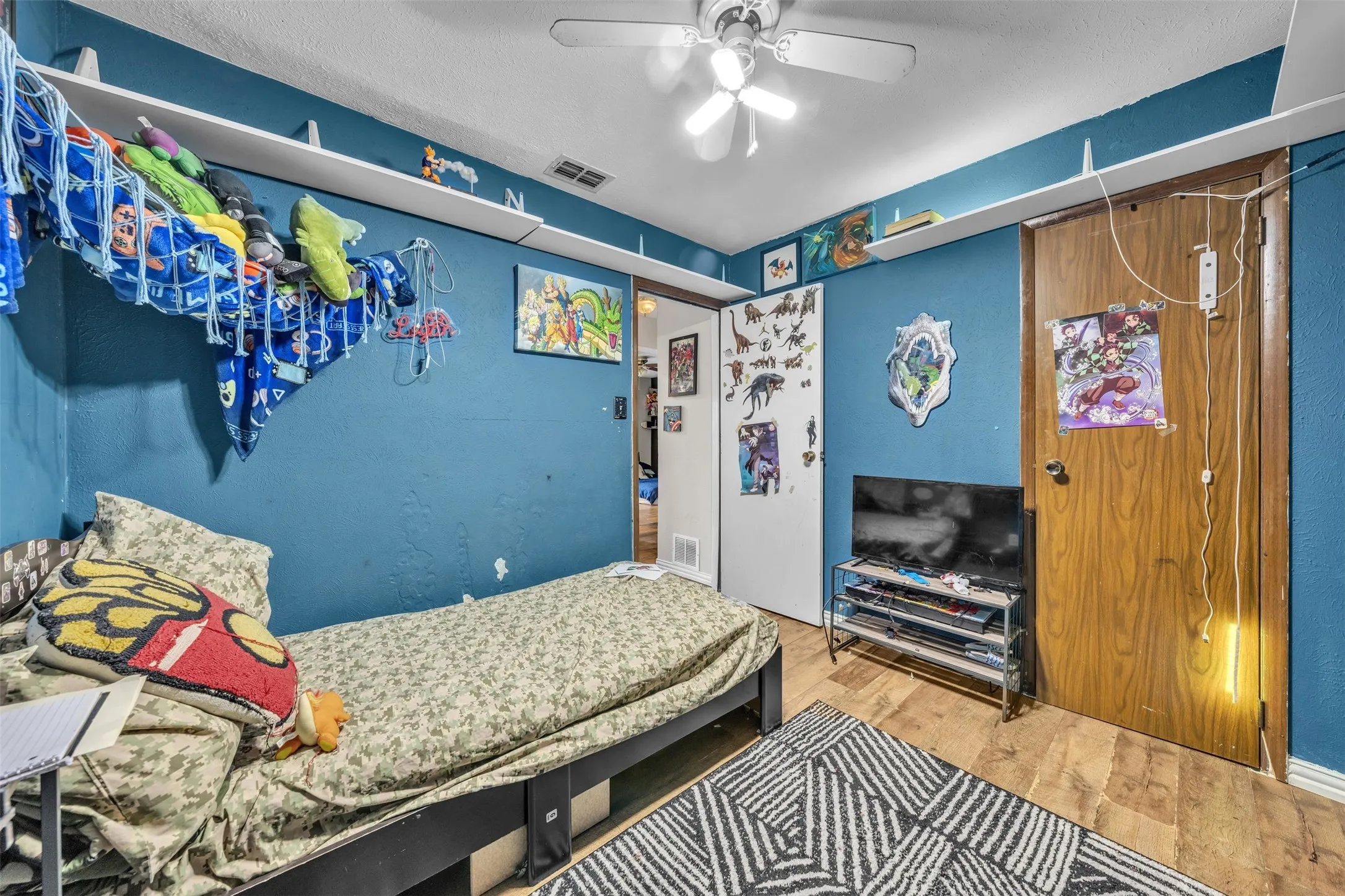 Room featuring wood-finish flooring, a ceiling fan, and blue painted walls