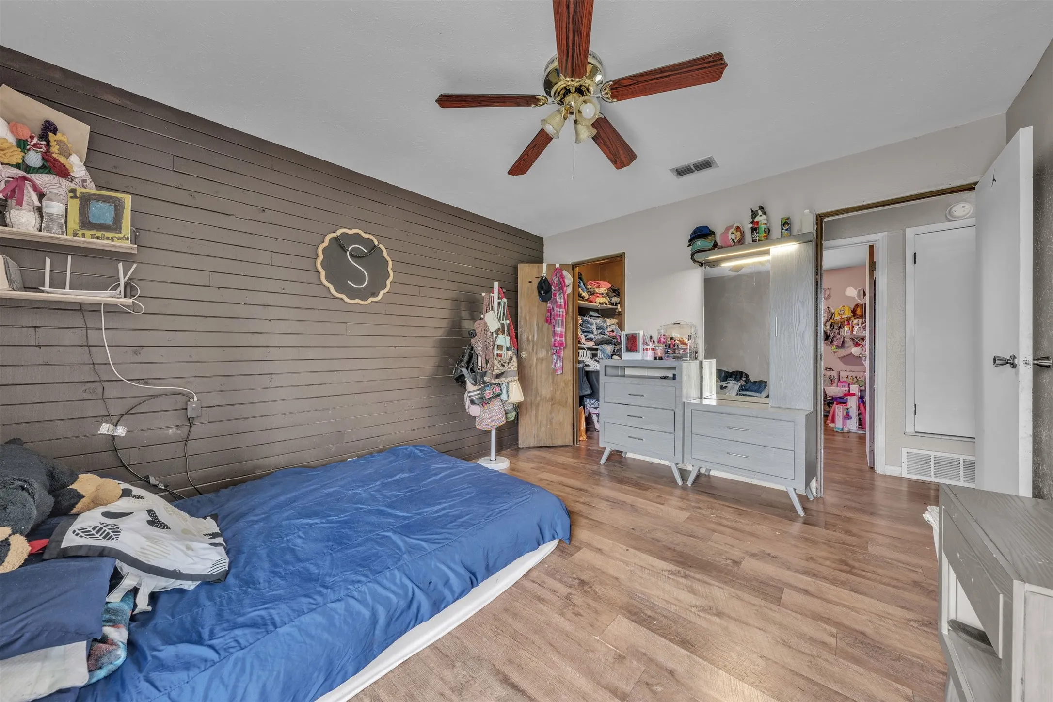 Bedroom featuring wood-finish flooring, a ceiling fan, and a shiplap accent wall