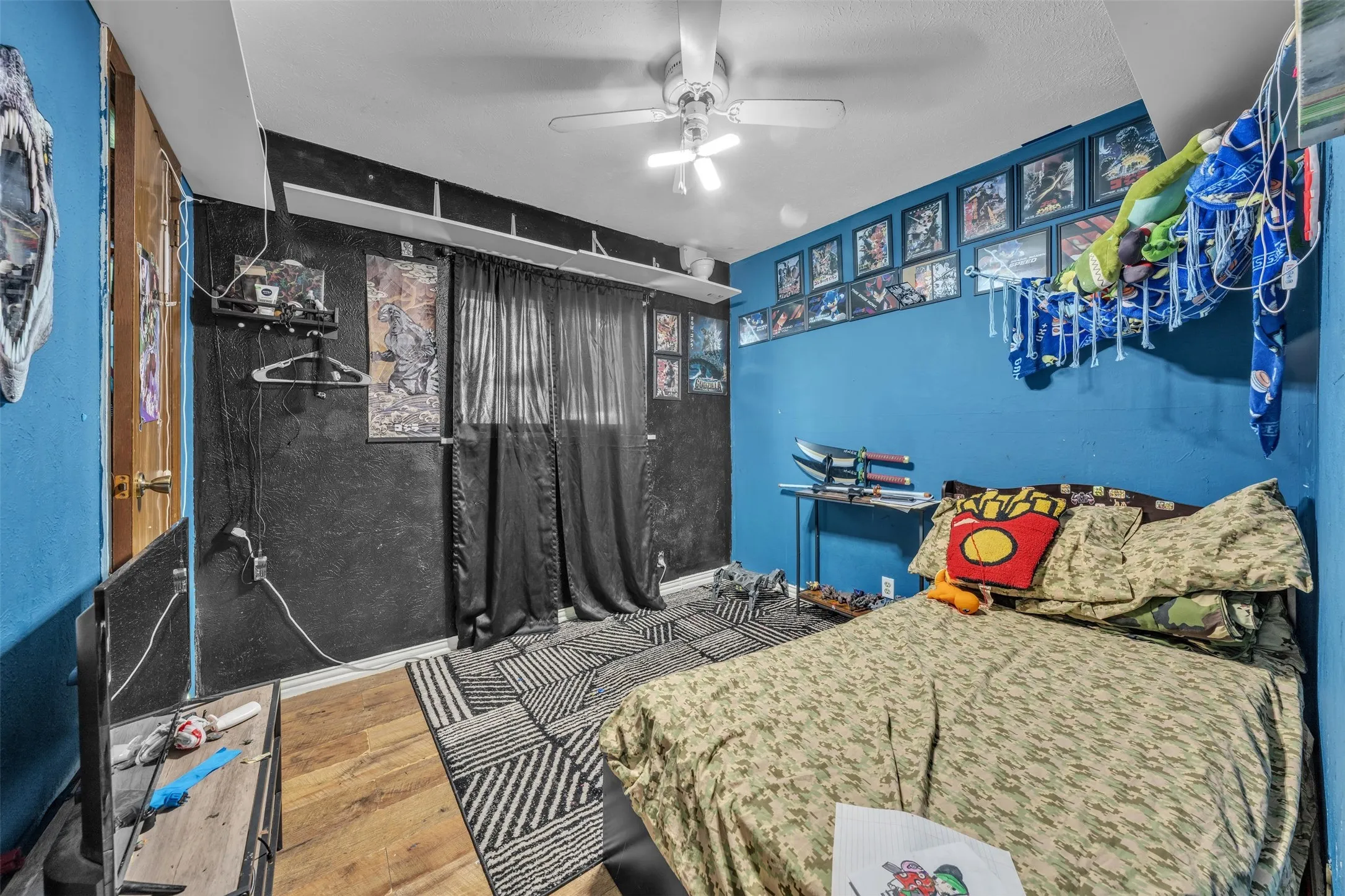 Room featuring wood-finish flooring, a ceiling fan, and a light-toned door