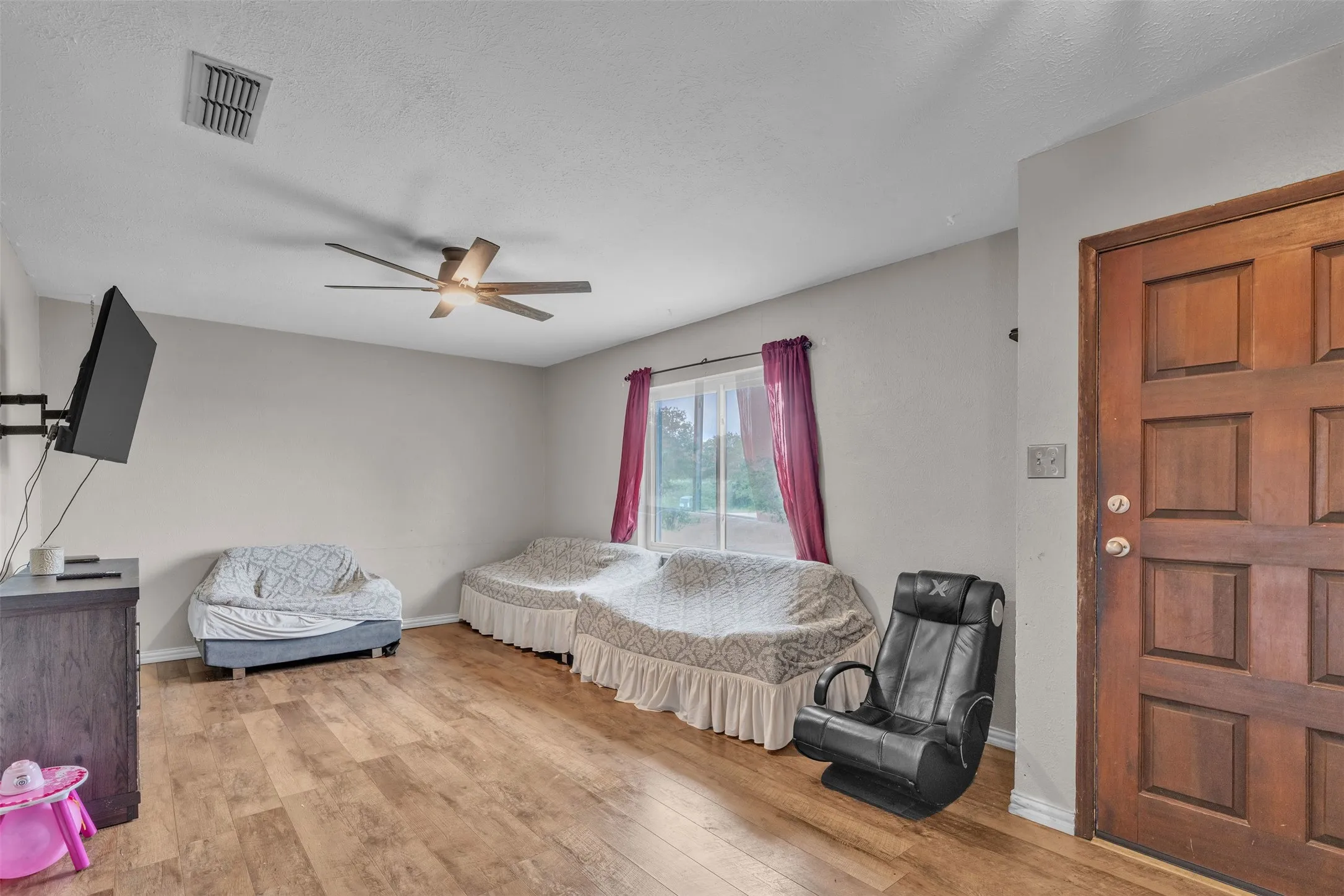 Living area featuring wood-finish flooring, a multi-paneled entry door, window with natural light, and a ceiling fan with integrated lighting