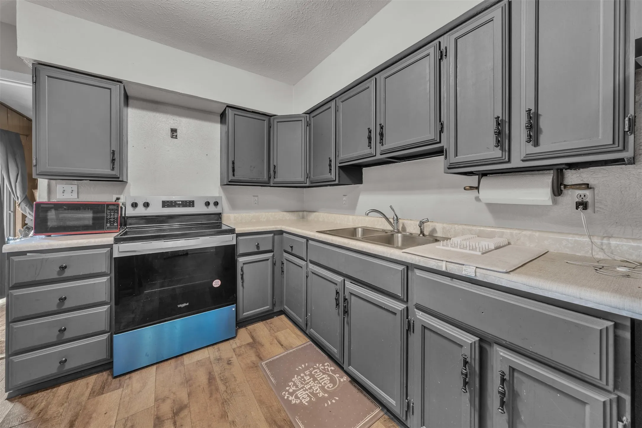 Kitchen featuring wood-finish flooring, gray cabinetry with black hardware, and a stainless steel sink