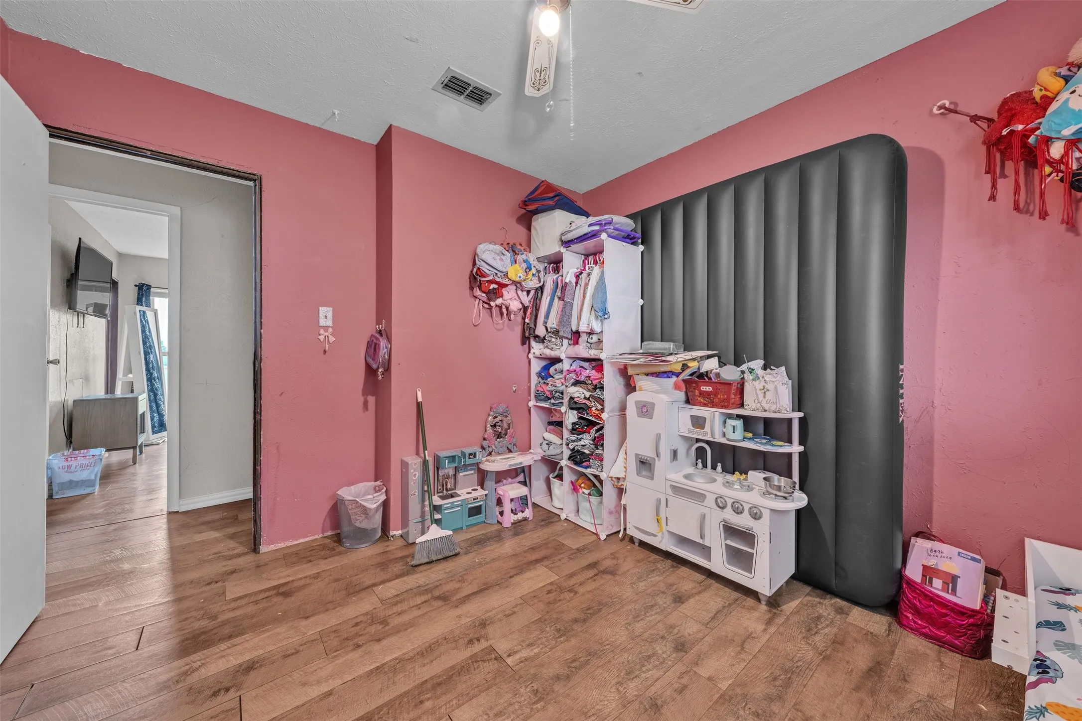 Room featuring wood-finish flooring, a light-colored ceiling, and a doorway opening to another interior​​‌​​​​‌​​‌‌​‌‌​​​‌‌​‌​‌​‌​​​‌​​ space