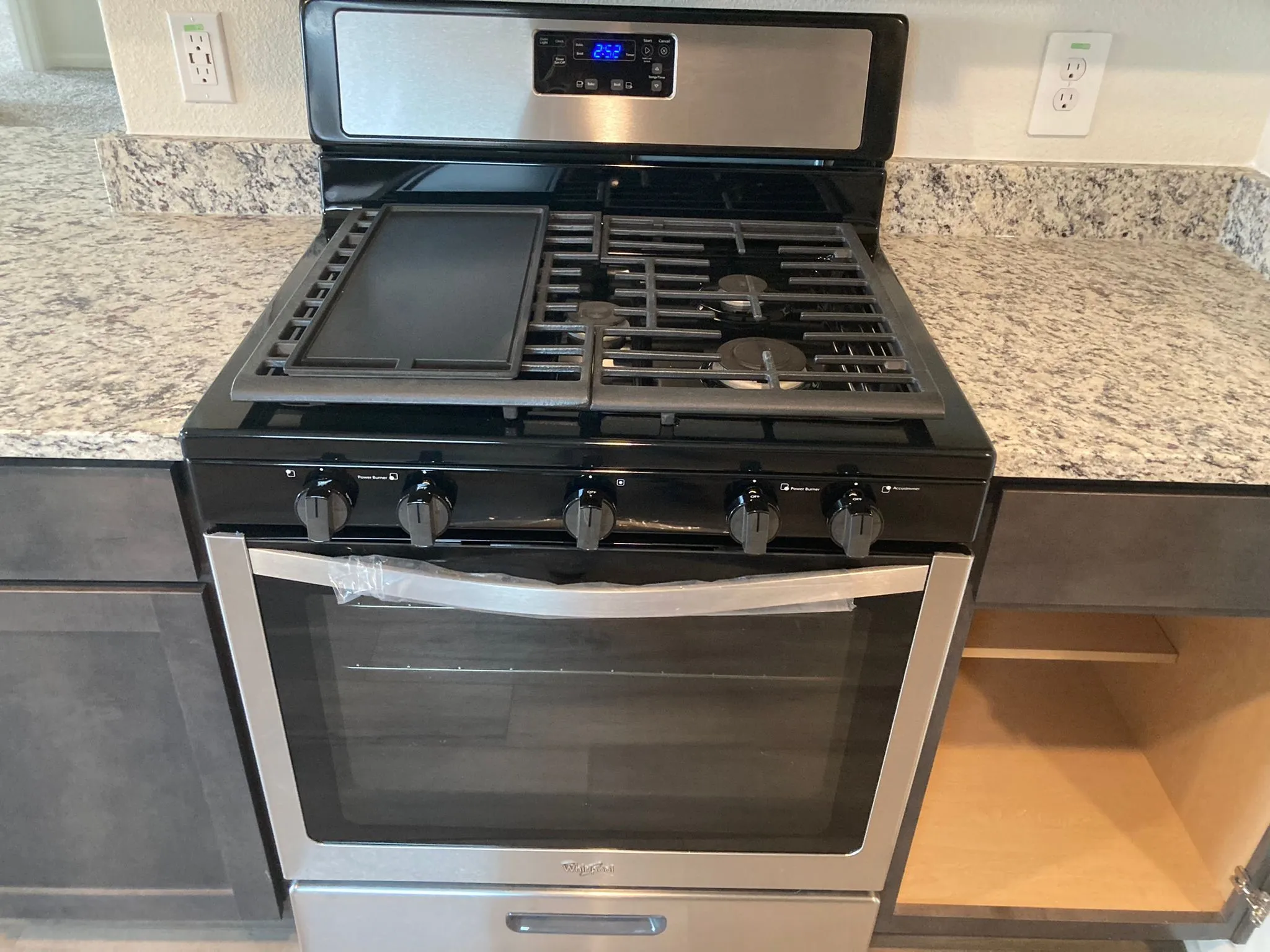 Stainless steel and black range with a griddle feature, set within speckled countertops