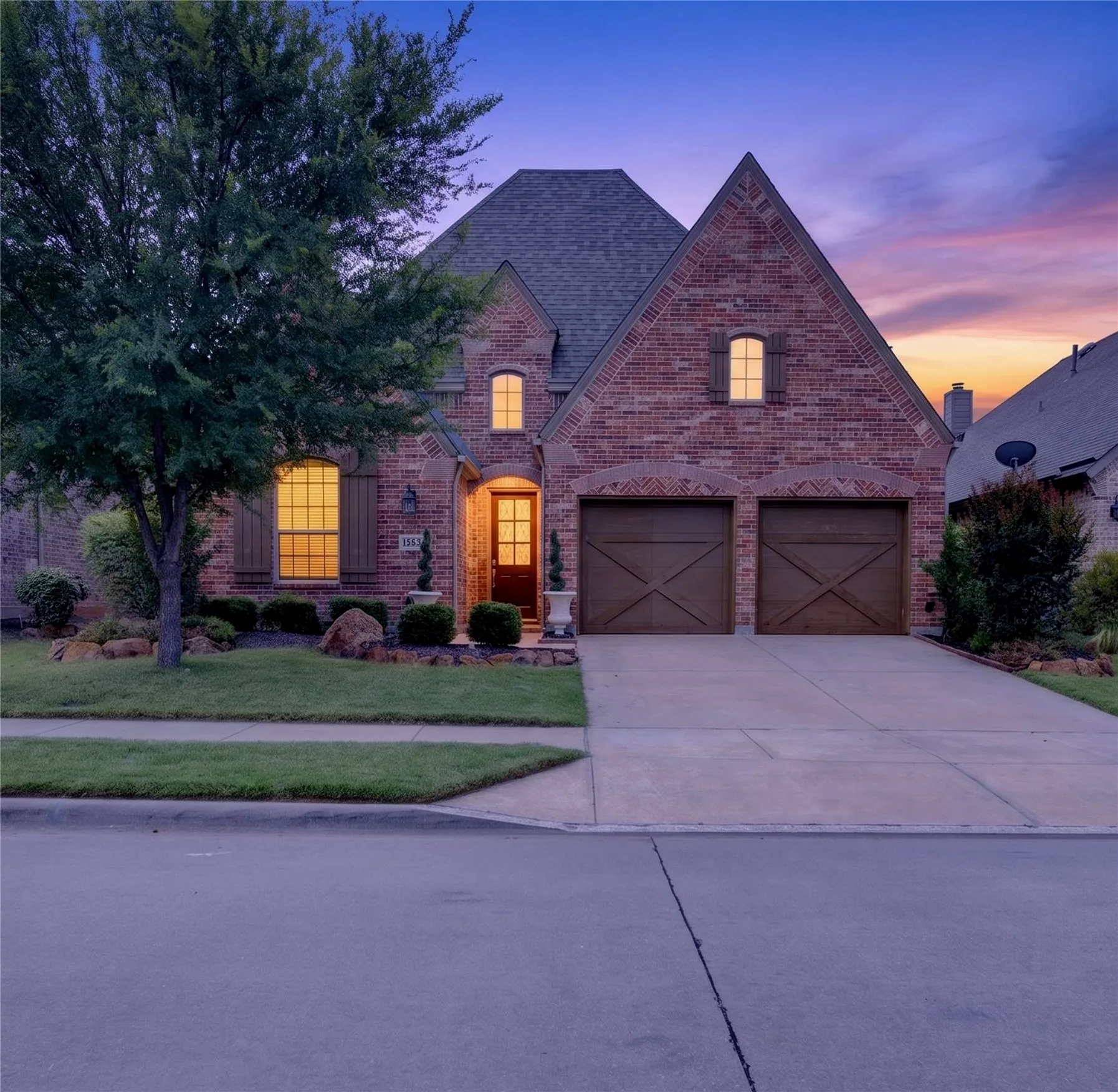 Brick exterior featuring multiple gables, a shingled roof, and a two-car garage with wood-finish doors