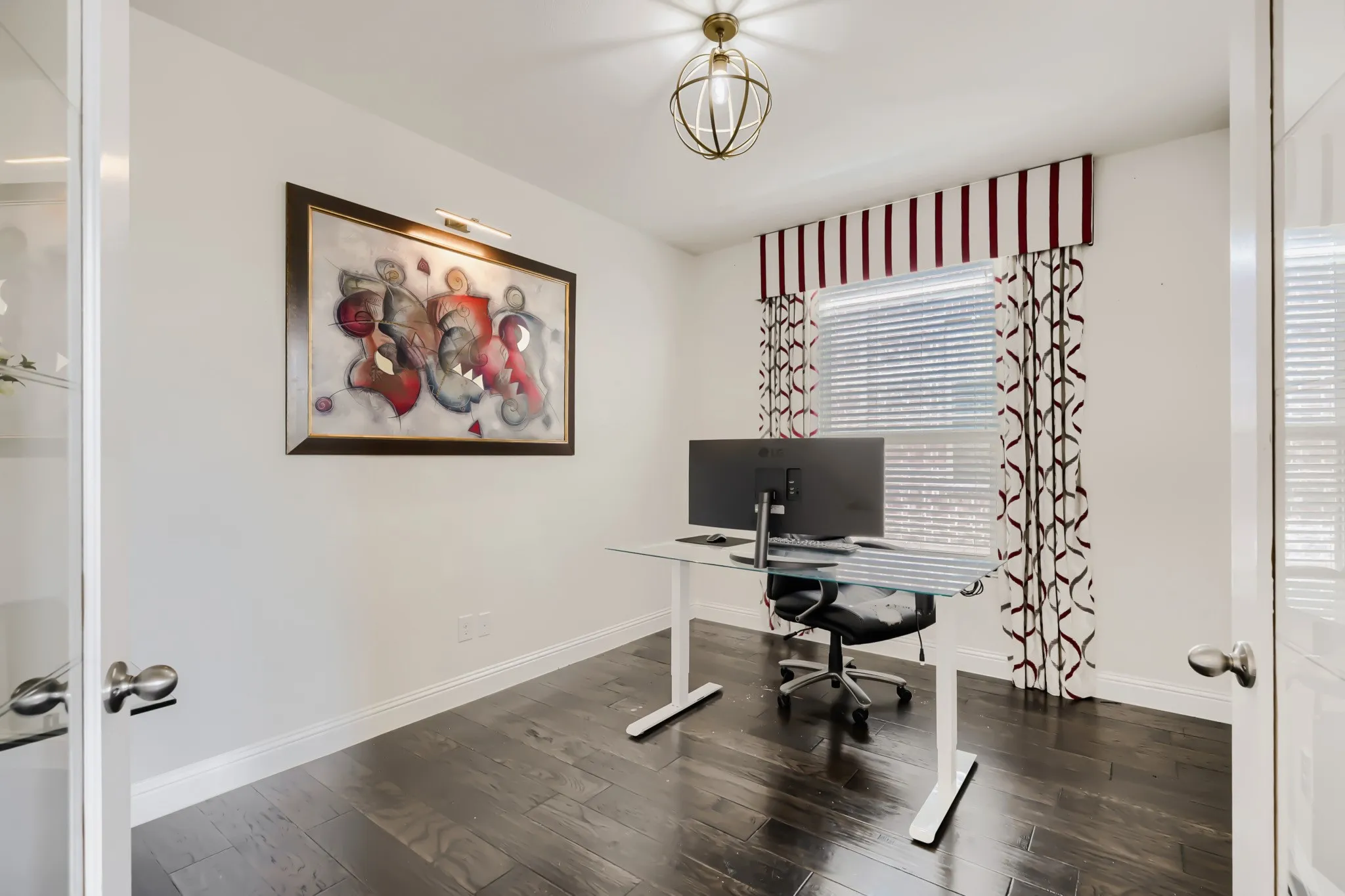 Hardwood-finish flooring, white baseboards, and a window with blinds