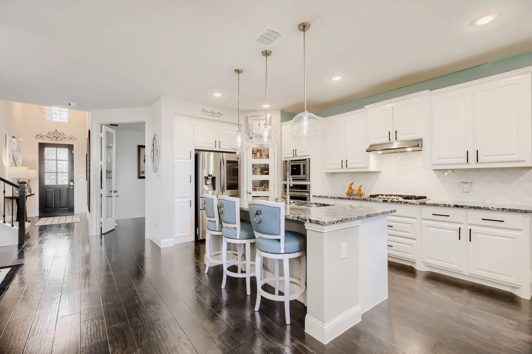 Kitchen featuring white cabinetry, stainless steel appliances, granite countertops, and a subway tile backsplash