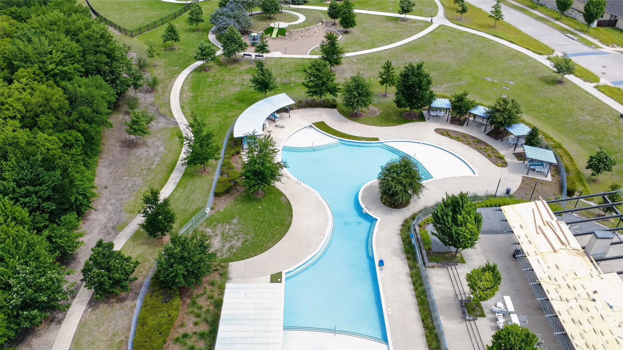Community swimming pool featuring a curvilinear design with integrated lounging areas