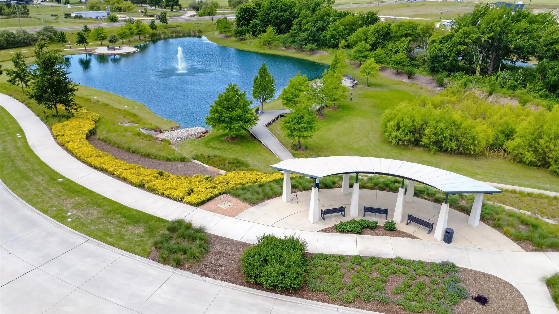 Community pond with fountain, pedestrian walkways, and a covered gathering area featuring multiple​​‌​​​​‌​​‌‌​‌‌​​​‌‌​‌​‌​‌​​​‌​​ benches