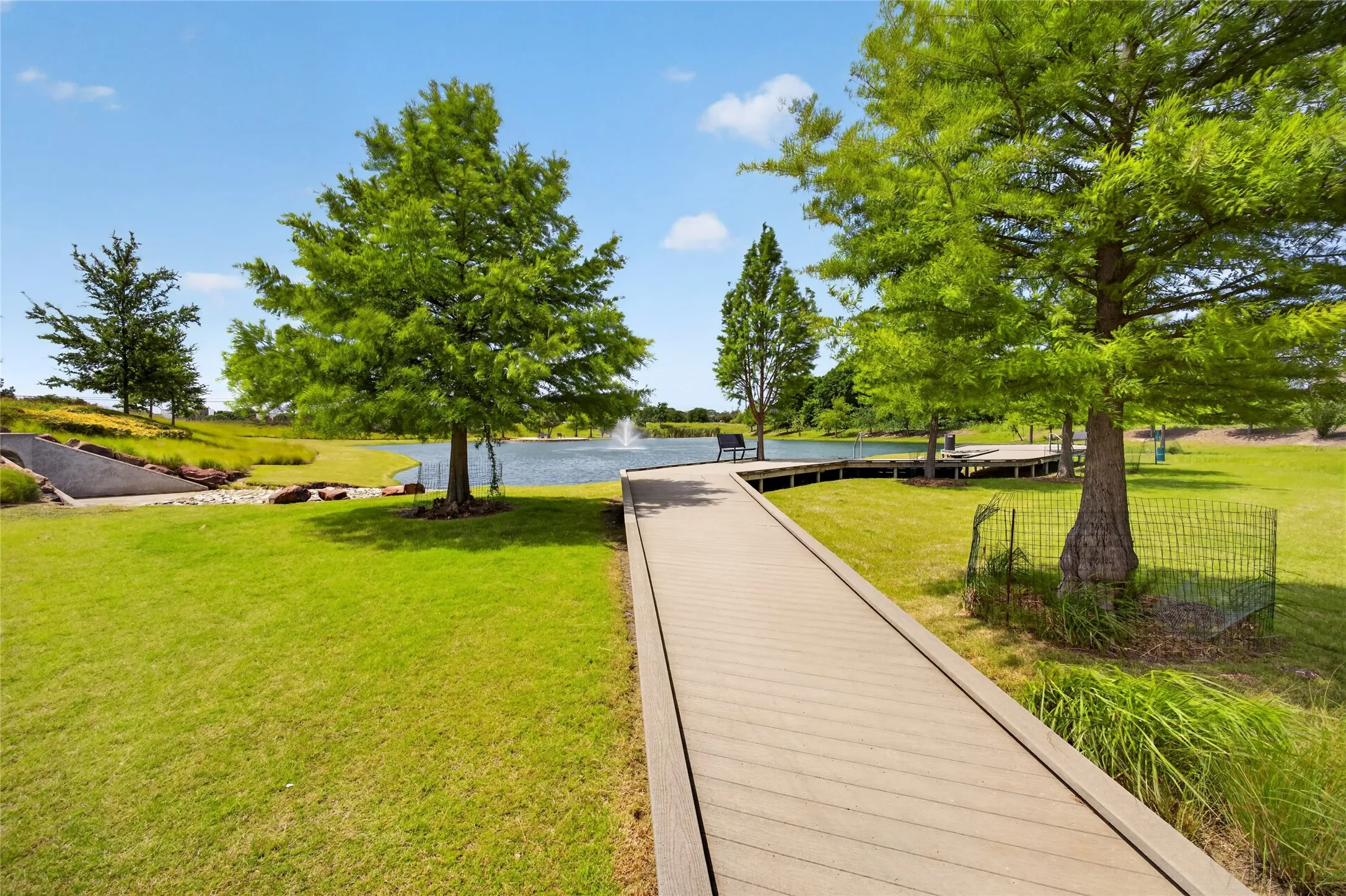 Boardwalk path extending over a body of water with a fountain feature