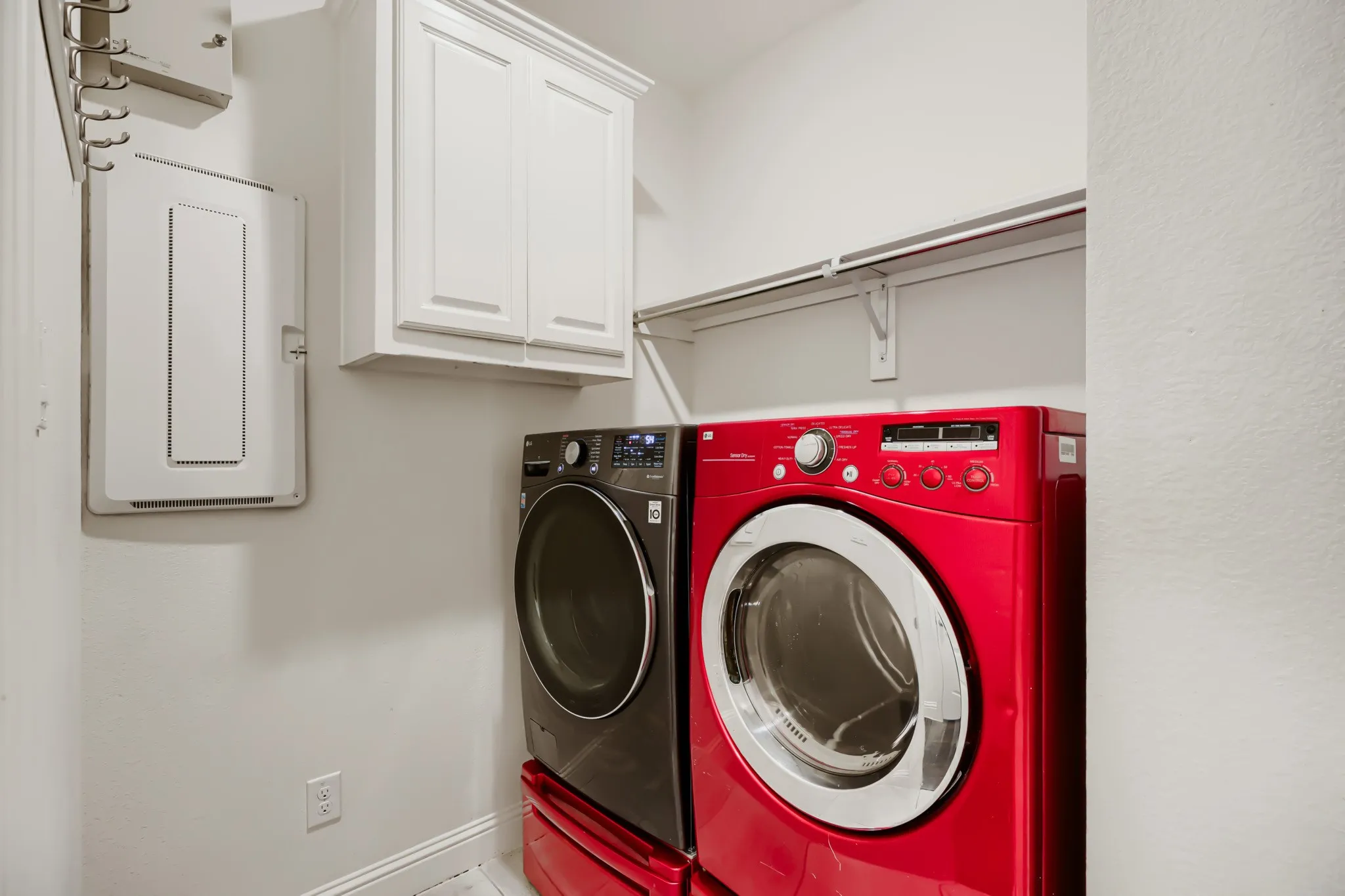 Dedicated laundry area featuring white upper cabinetry, a wall-mounted drying rack, and a built-in shelf