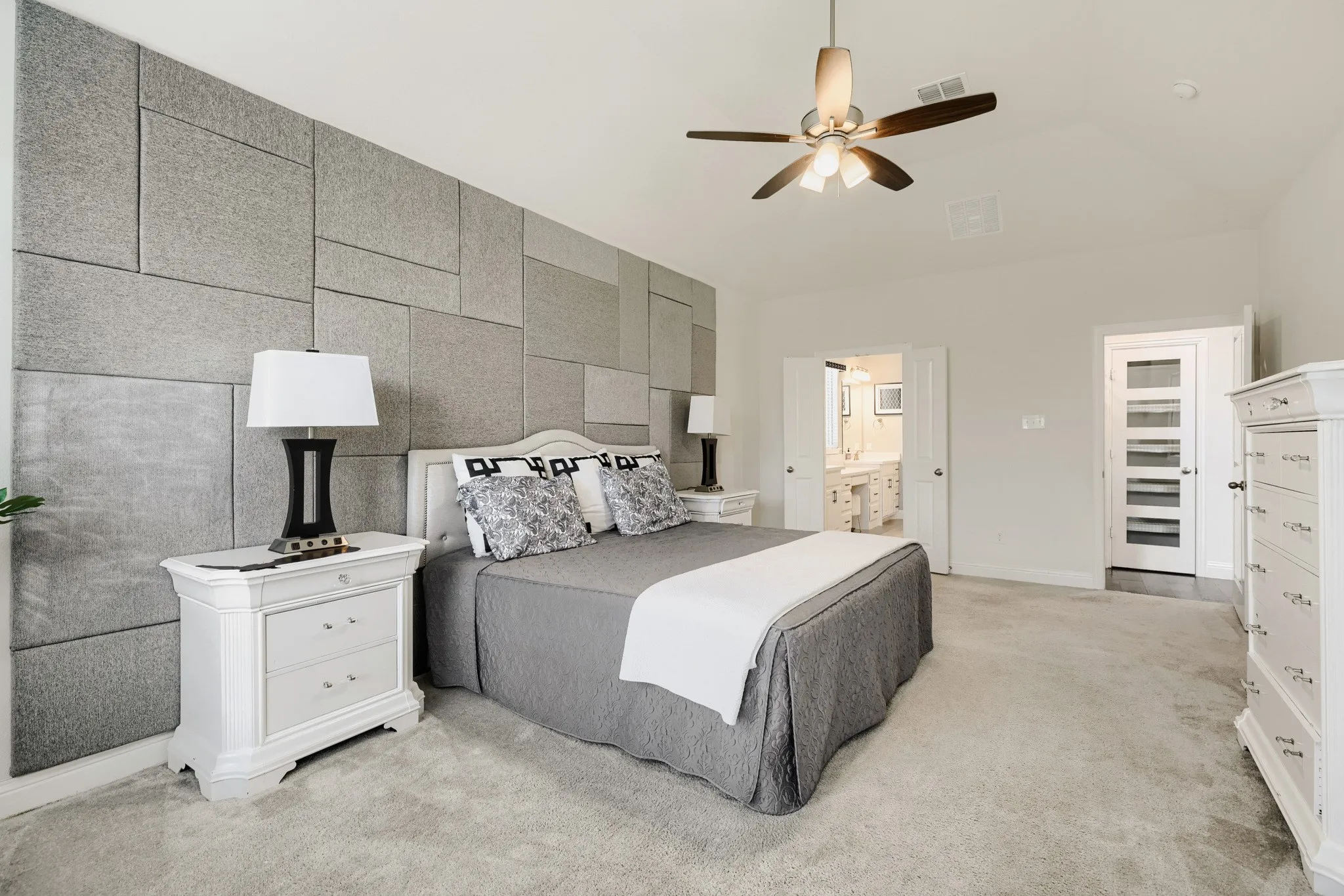 Bedroom featuring a textured accent wall, vaulted ceiling, and carpeted flooring
