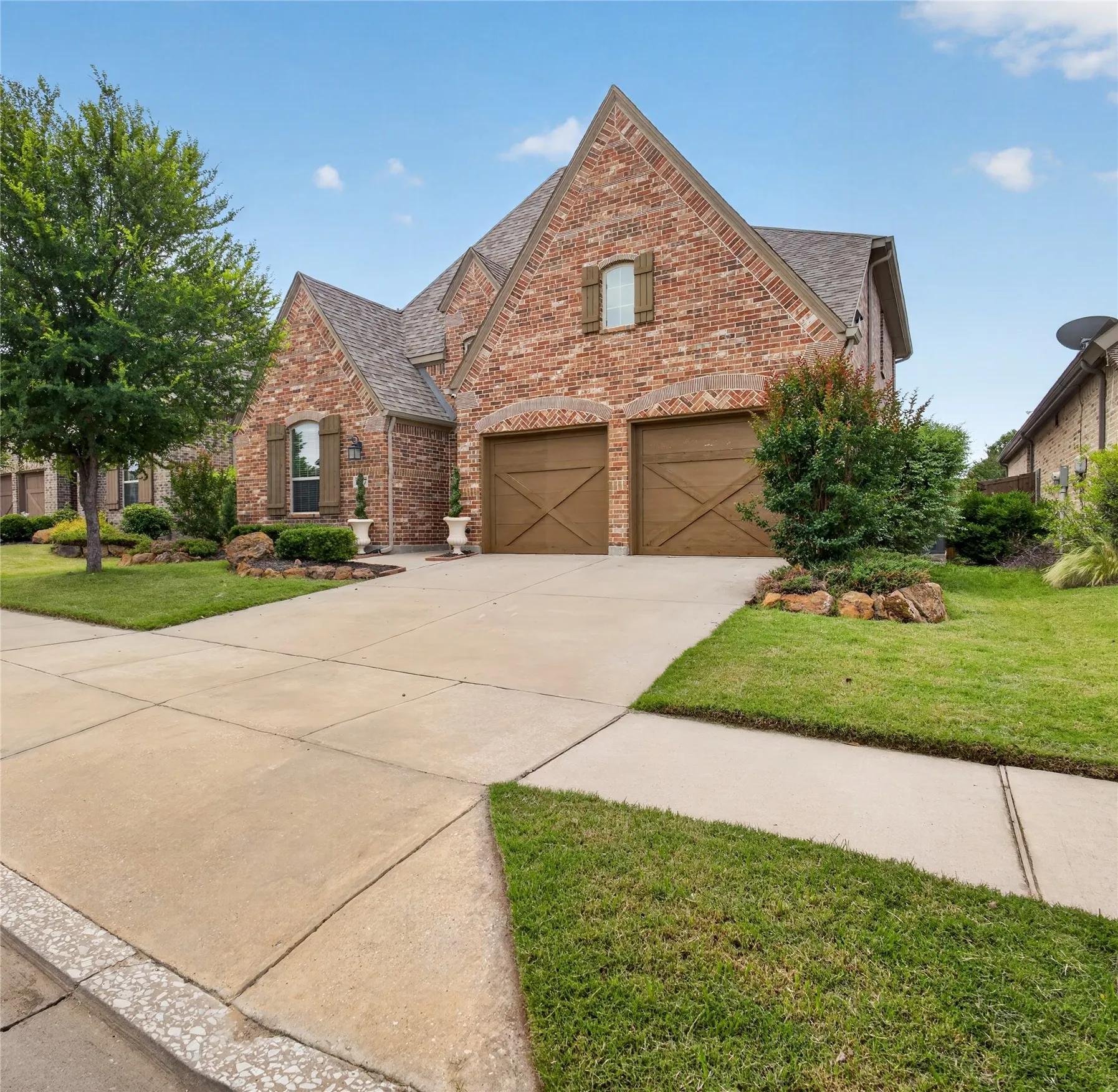 Brick exterior with a shingle roof and a two-car garage featuring wood-finish doors