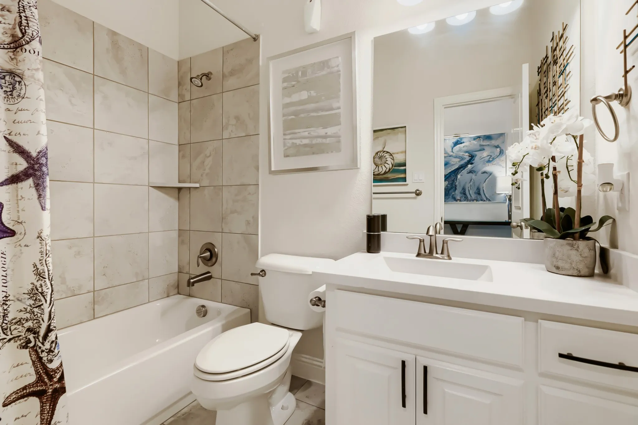 Bathroom featuring a white vanity with an integrated sink and brushed nickel faucet, a large wall mirror, and a white toilet