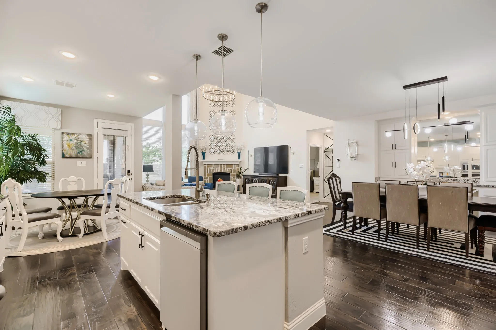 Kitchen island featuring a granite countertop, undermount sink, and three pendant light fixtures