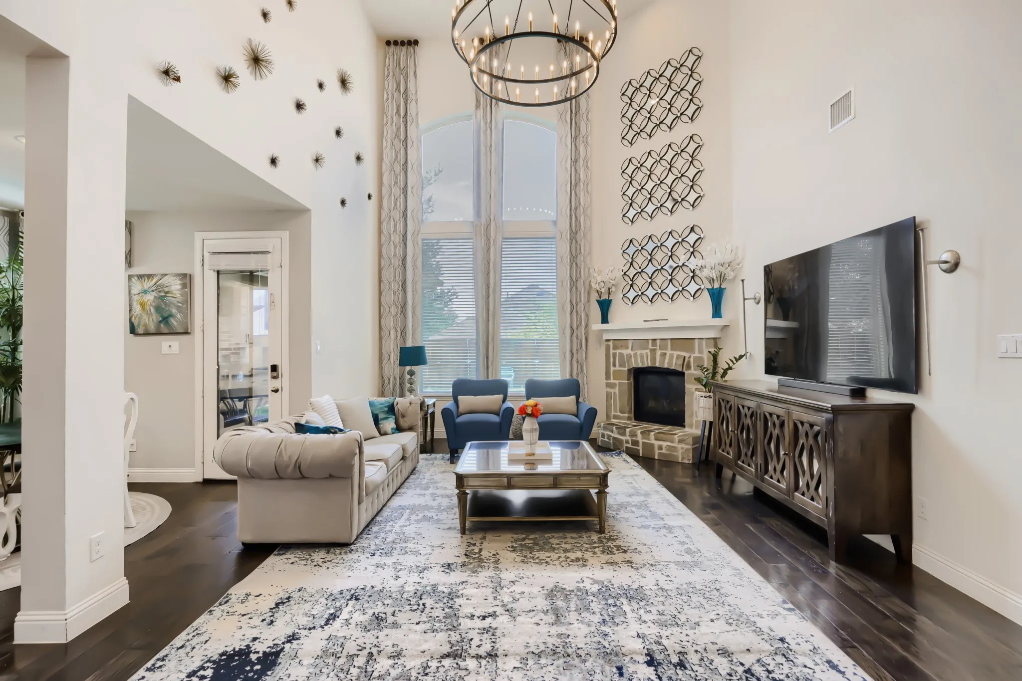 Spacious living area featuring soaring ceilings, a prominent stone-clad fireplace, and expansive windows