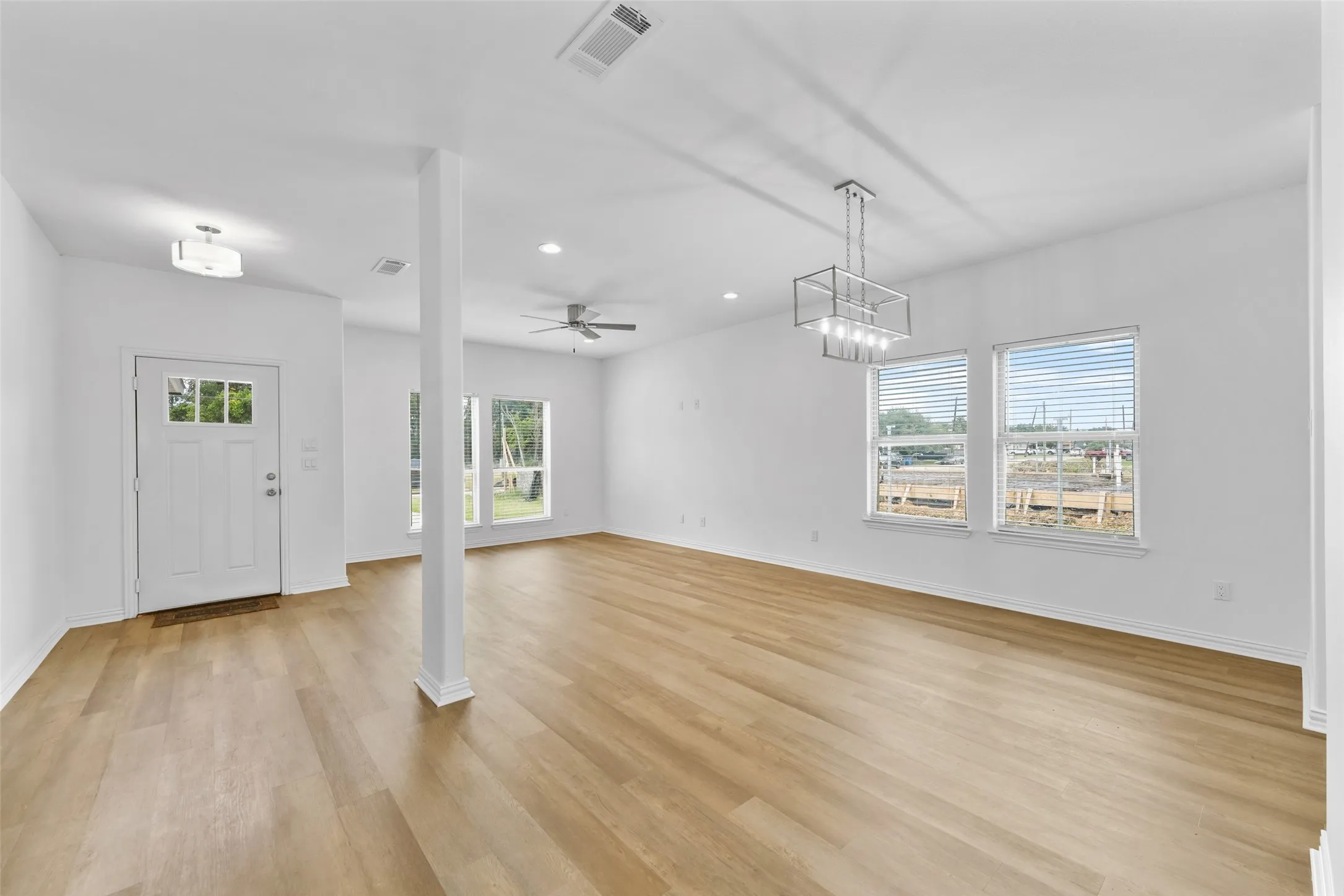 Spacious interior featuring wood-finish flooring, white walls, and multiple windows with blinds