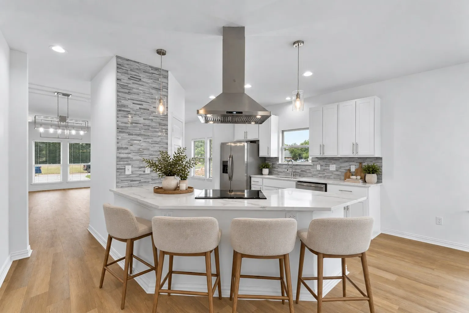 Contemporary kitchen featuring a large island with cooktop, stainless steel range hood, white cabinetry, and wood-finish flooring