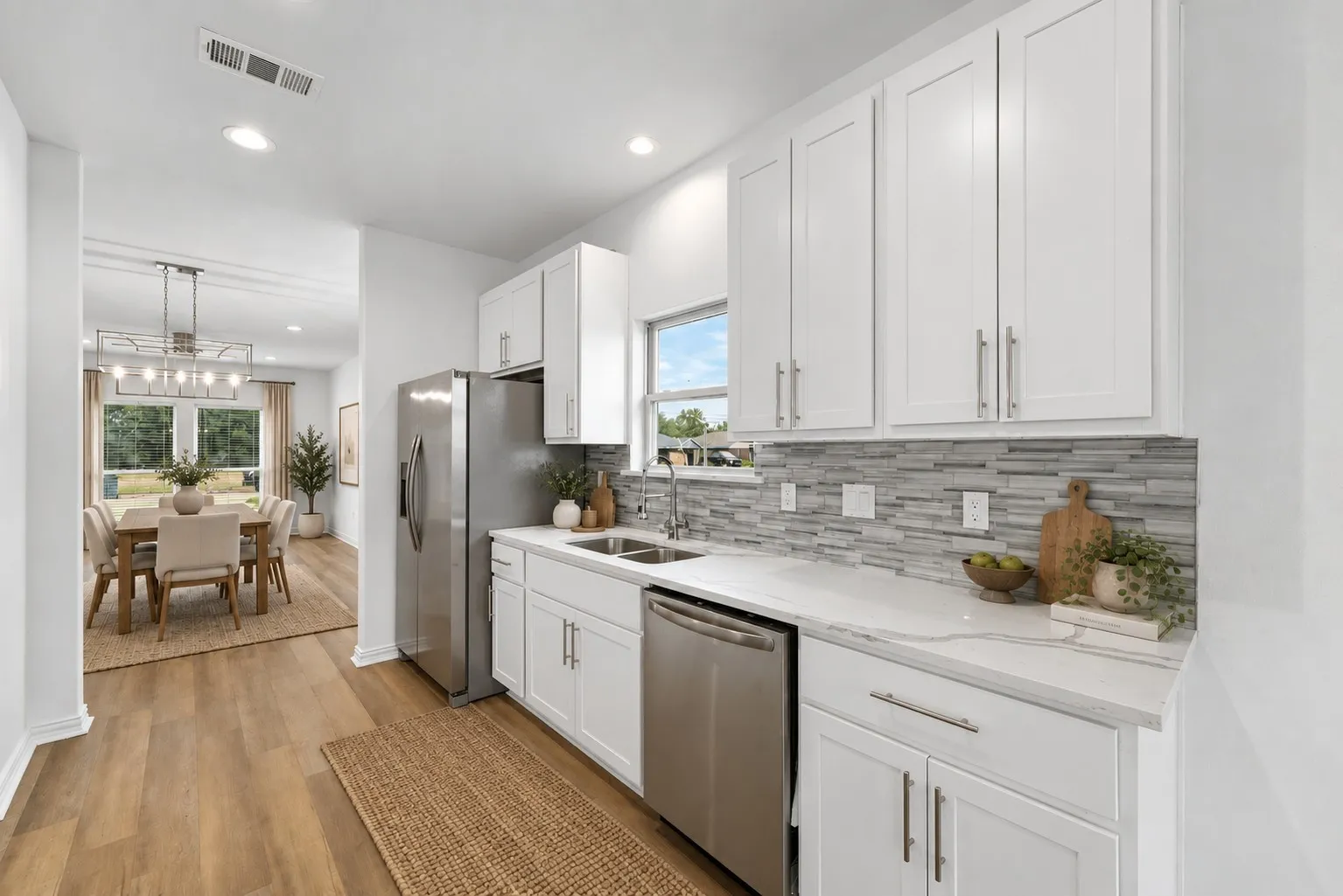 Kitchen with white cabinetry, stainless steel appliances, light-toned countertops, and a mosaic tile backsplash
