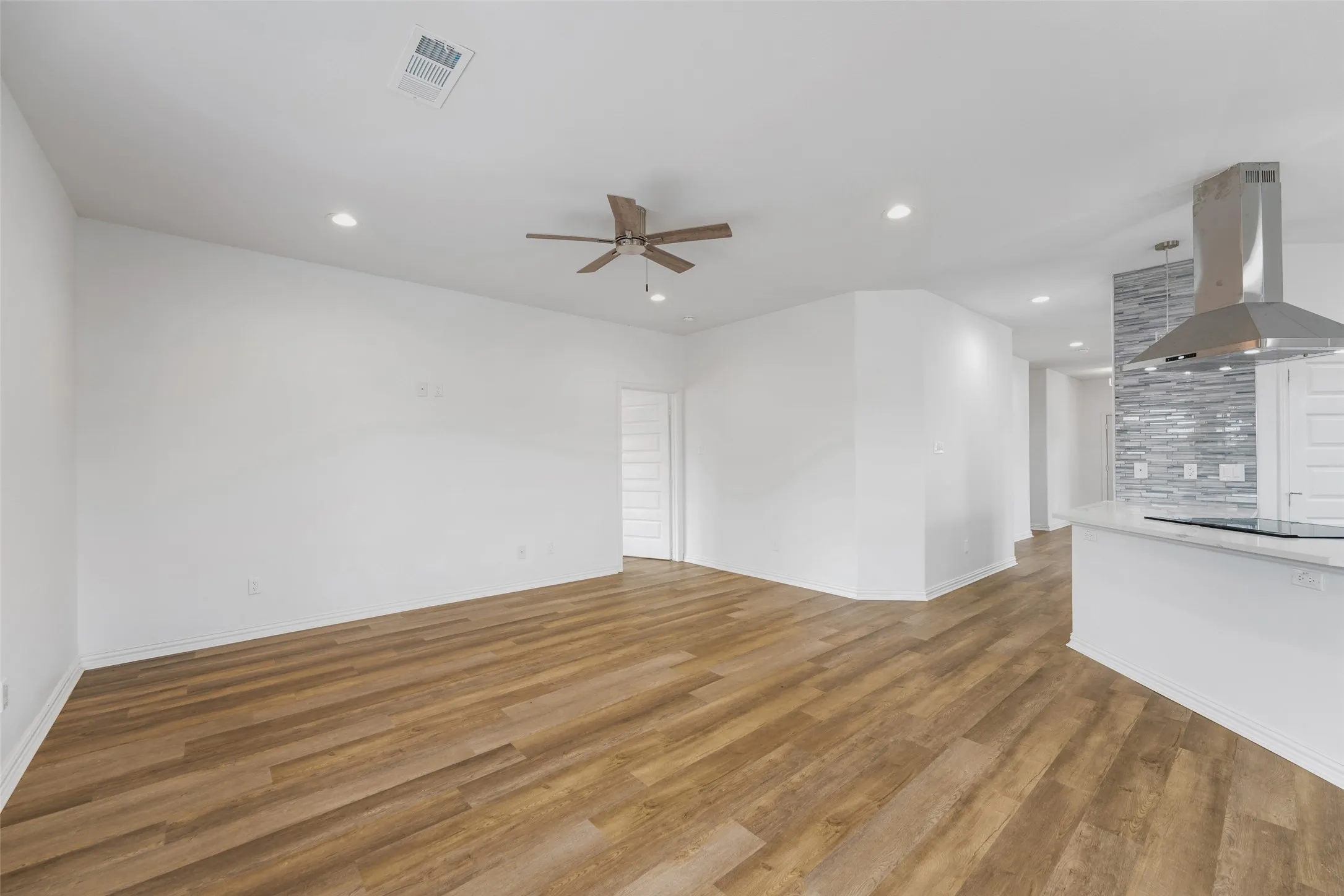 Open-concept living space featuring wood-finish flooring, recessed lighting, and a ceiling fan