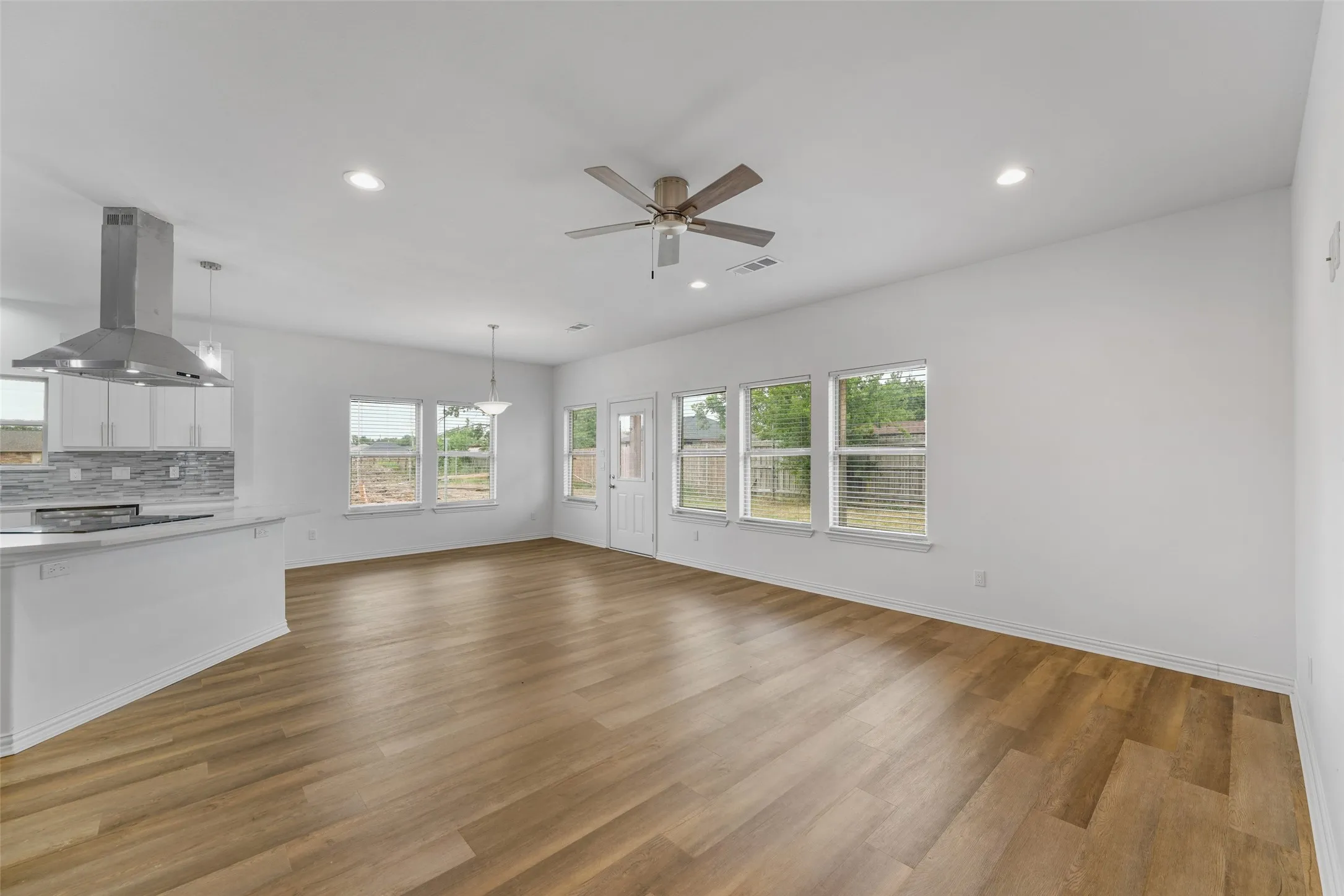 Bright living area with wood-finish flooring, recessed lighting, and a contemporary ceiling fan