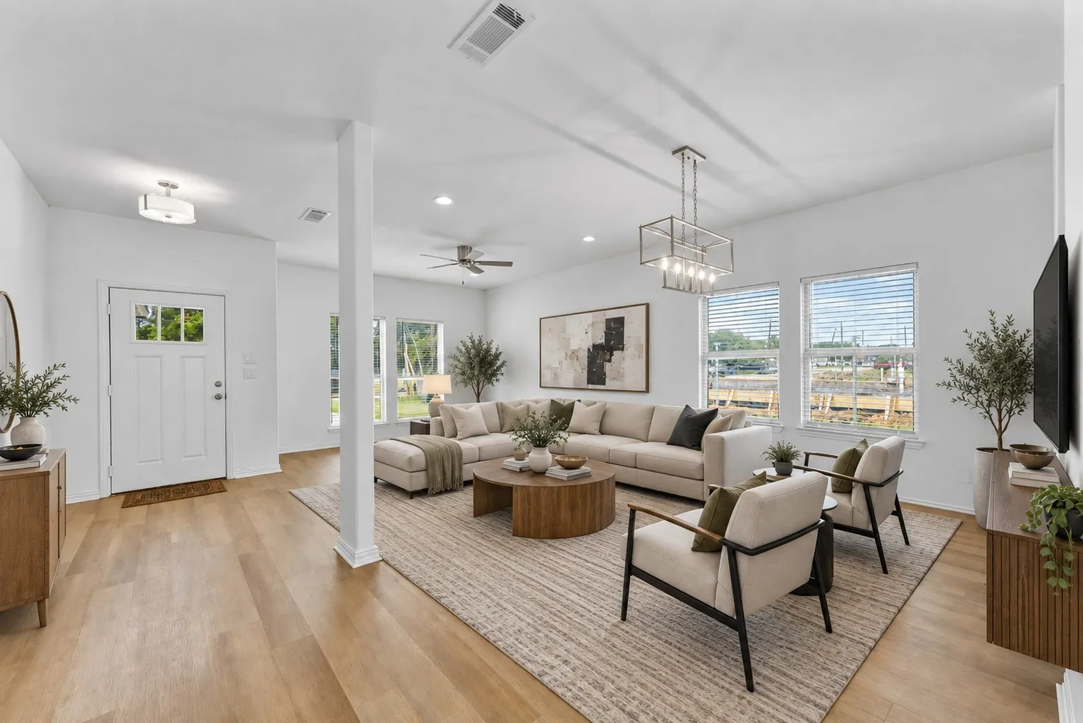 Open-concept living space with light wood-finish flooring, recessed lighting, and a modern rectangular chandelier