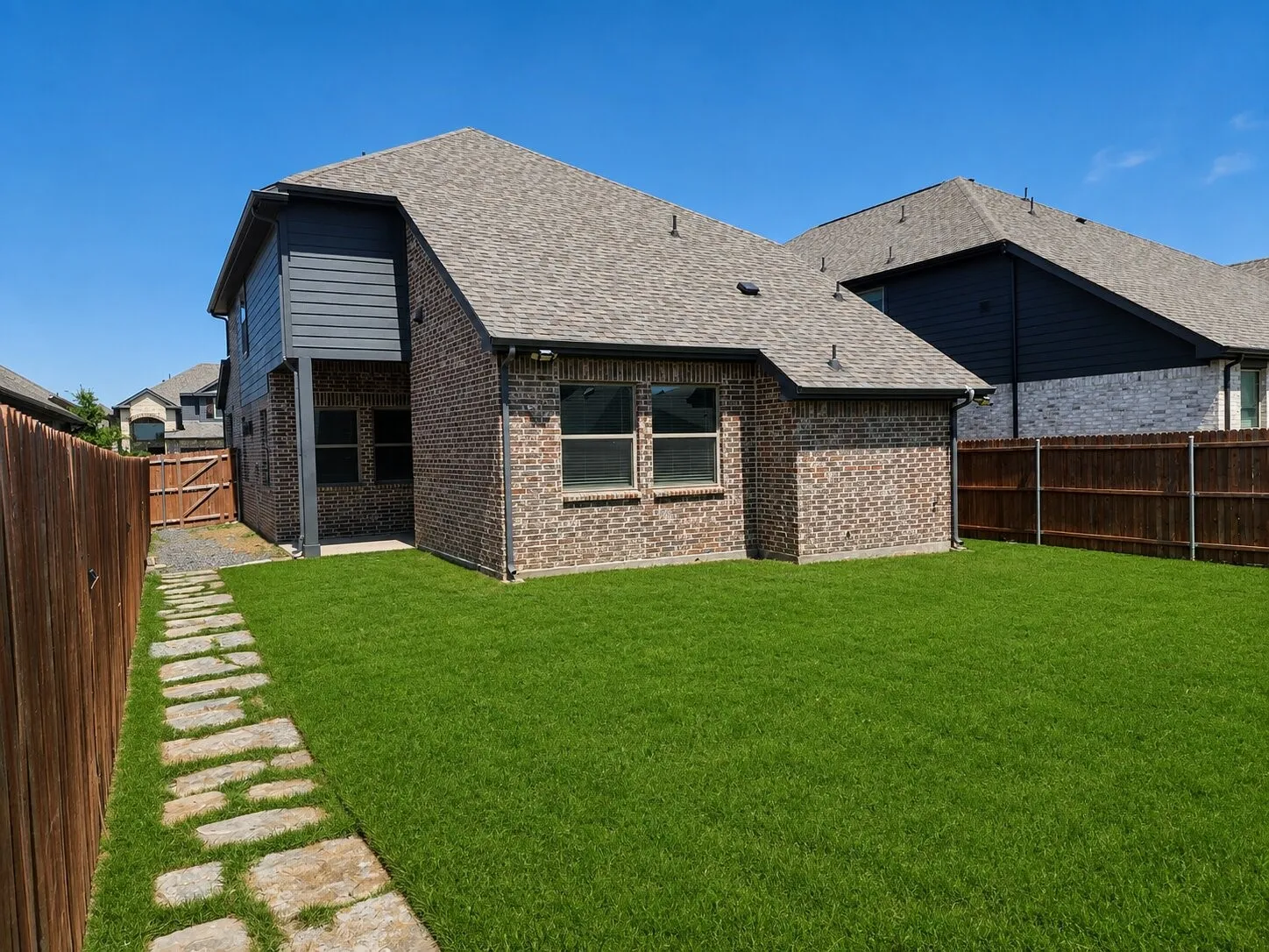 Expansive lawn with a stone pathway and privacy fencing