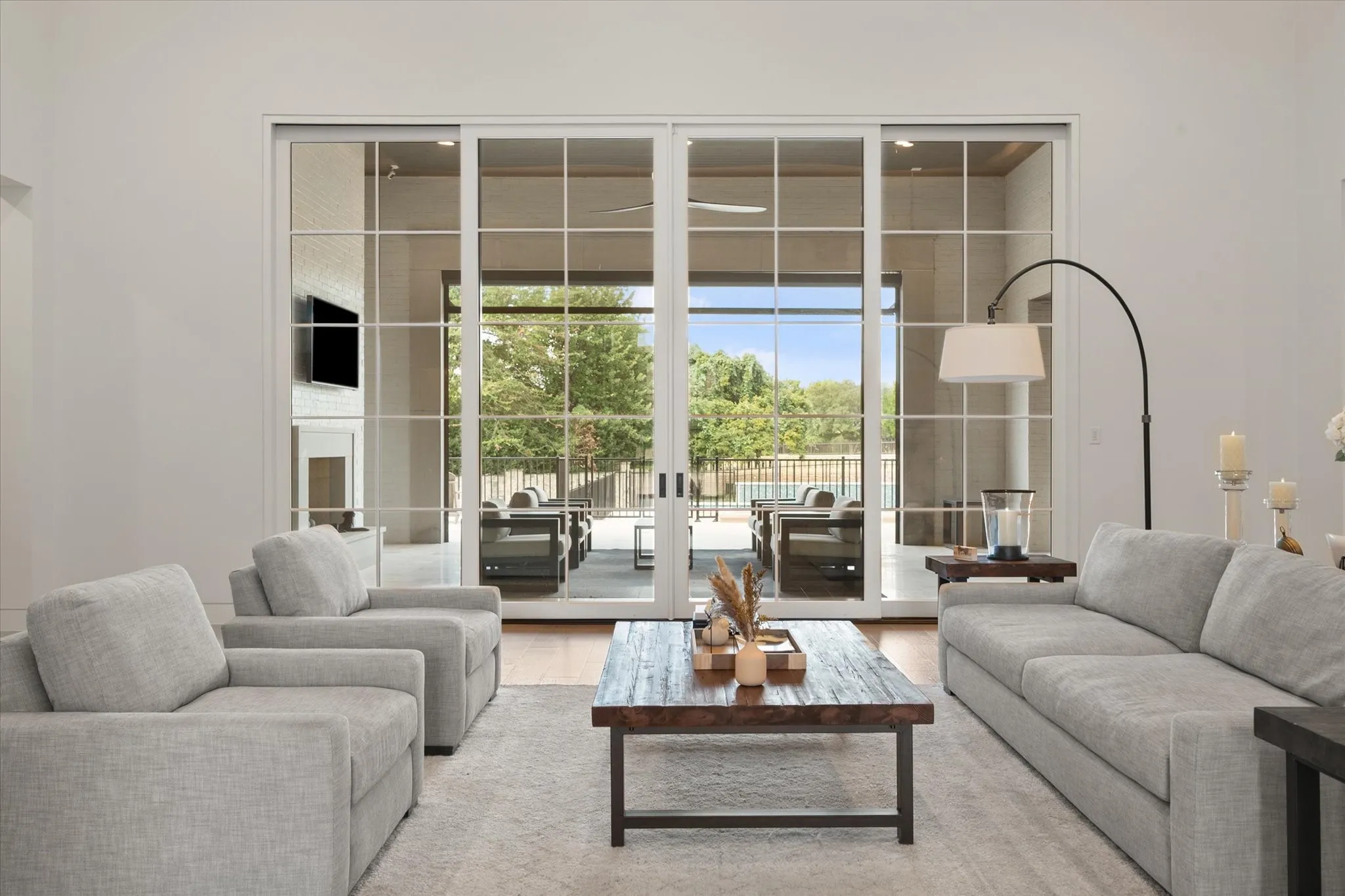 Large sliding glass door from living room area opening to an outdoor living area with television, fireplace, outdoor grill and more.