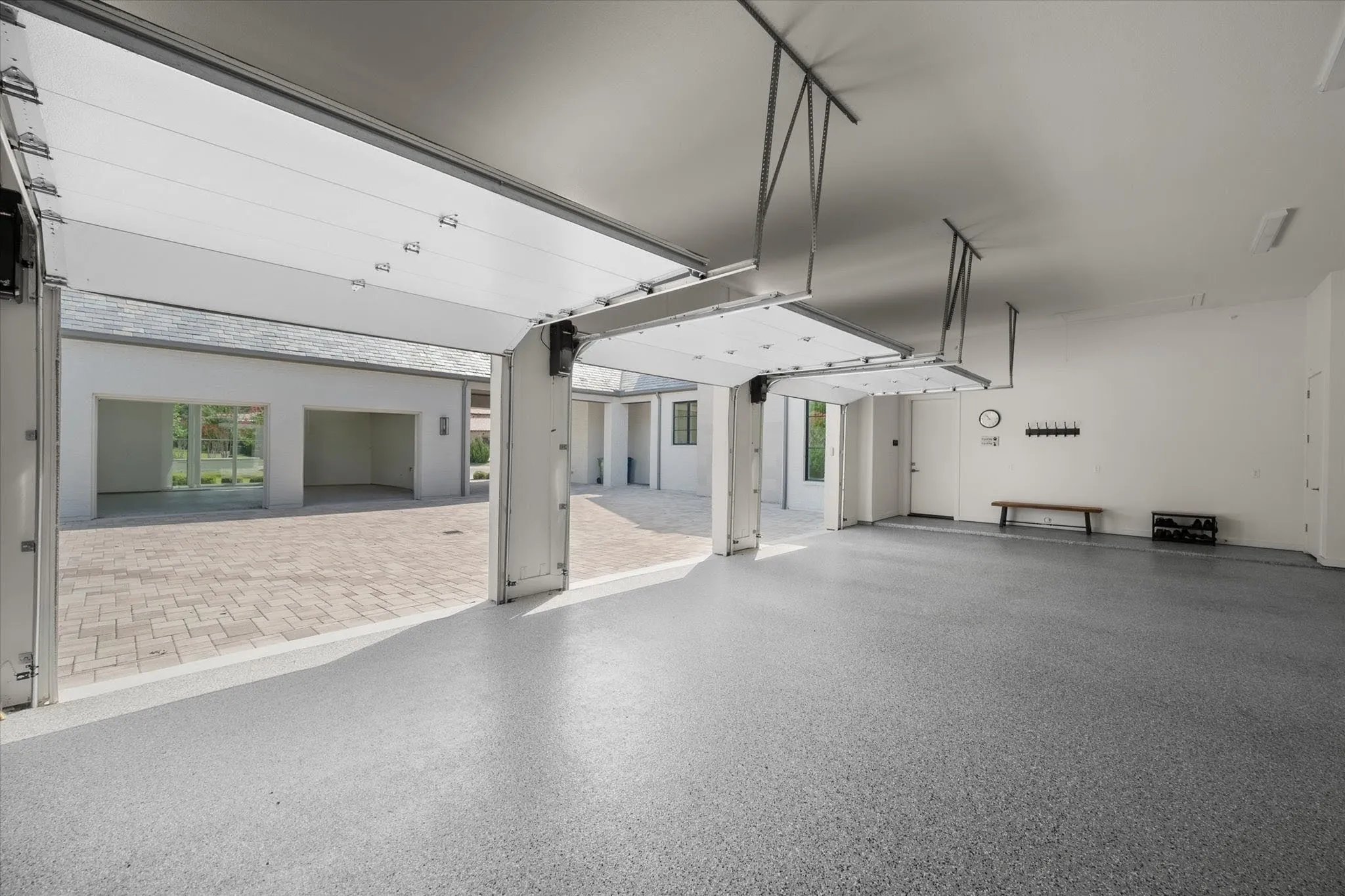 Spacious Five car garage configuration with three bays on one side and two bays on opposite side. Garage area is insulated and features a bay window and granite-look epoxy flooring.