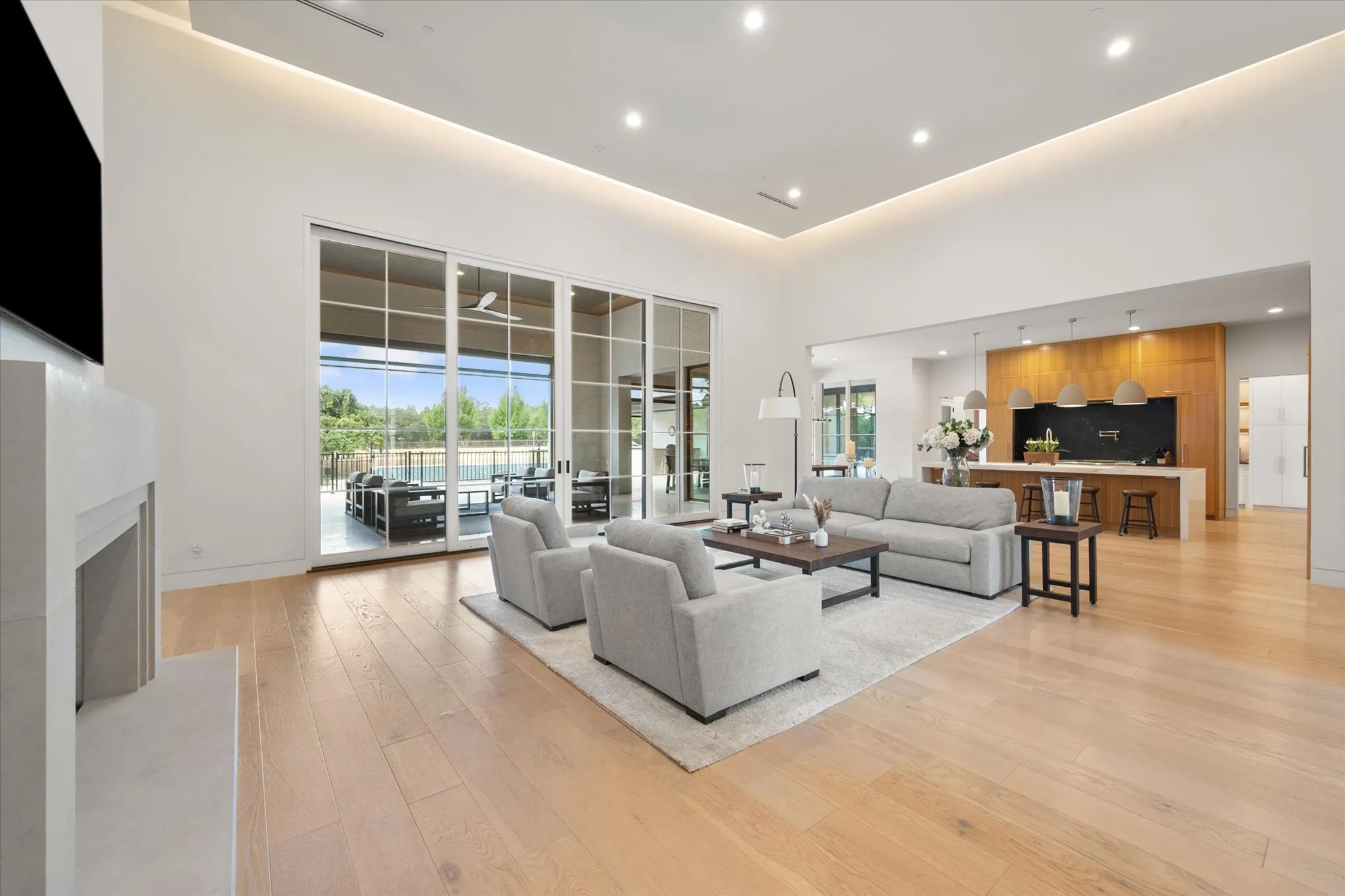 Living area featuring light wood finish flooring, a contemporary limestone fireplace, and recessed lighting. Power shades throughout the home.