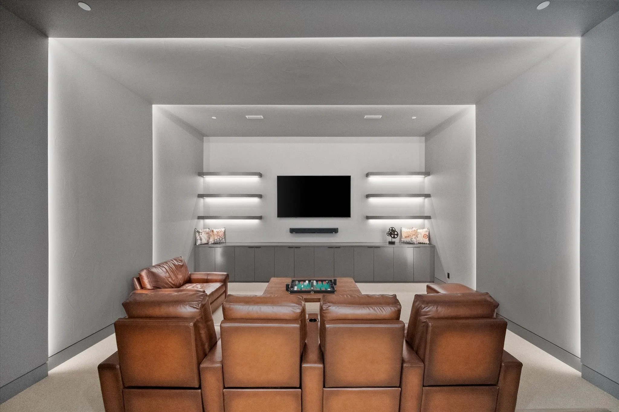 Recessed media wall with built-in shelving and integrated lighting. Featuring an 85-inch OLED mounted flat-screen and premium Sennheiser speaker system that can remain with the home.