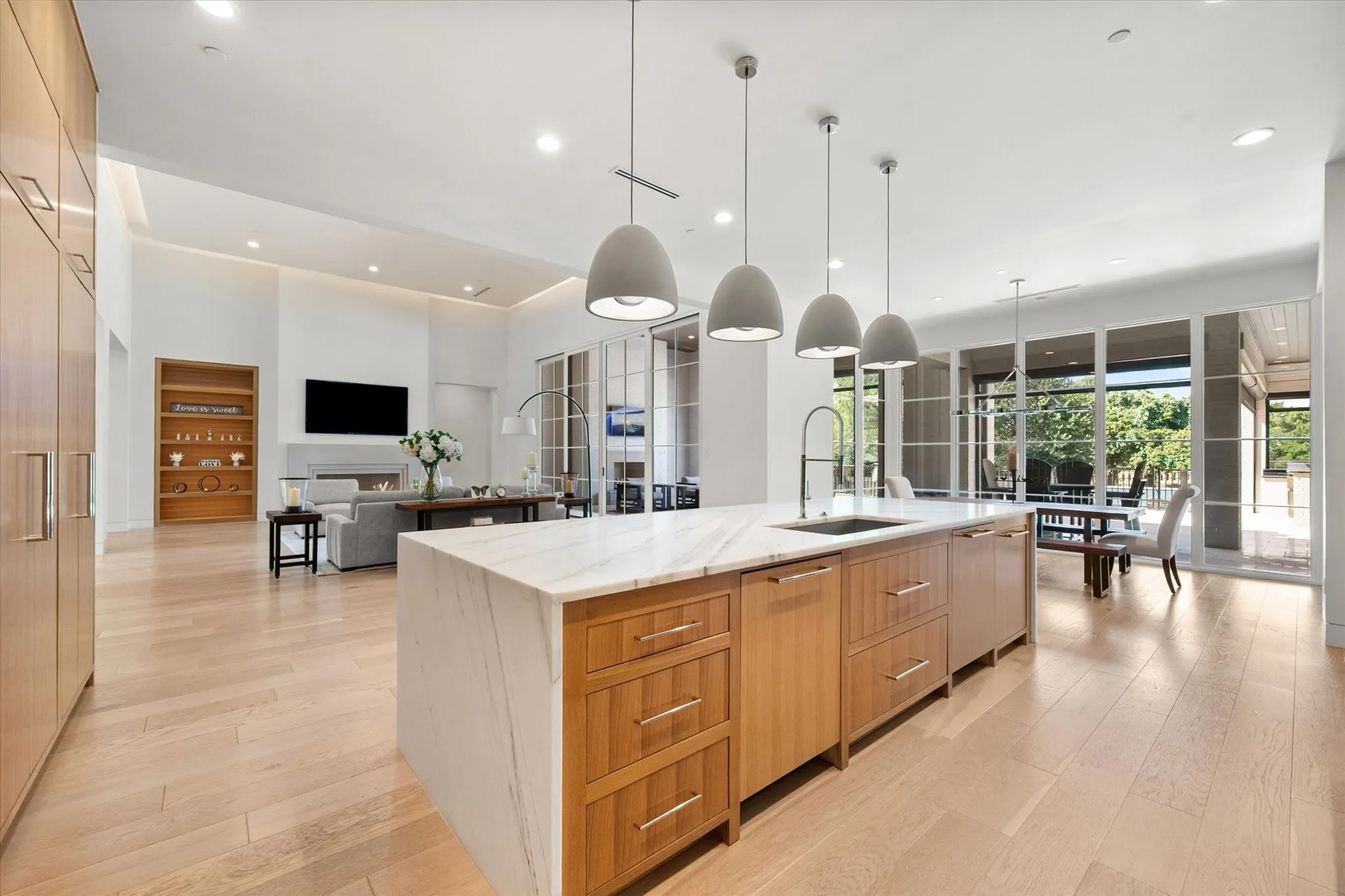 Kitchen island with a waterfall countertop, integrated sink, and modern pendant lighting