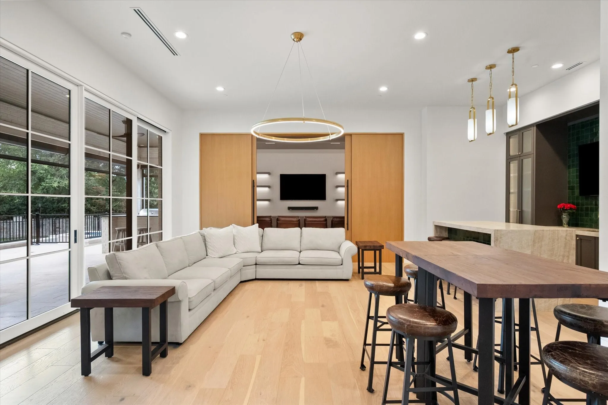 Spacious game room an living area featuring light wood-finish flooring, recessed lighting, and large sliding glass doors. View to Media room.