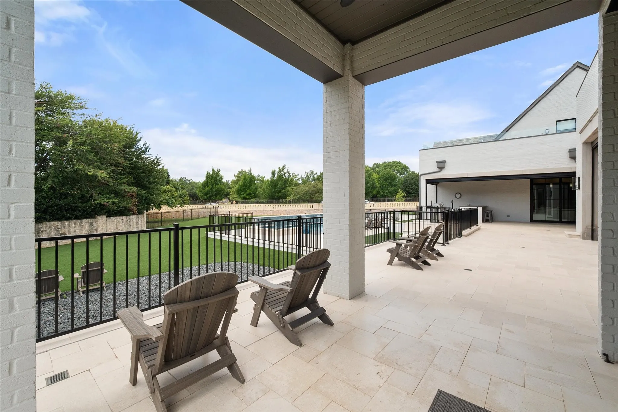 Expansive outdoor yard area with light-toned paving stones, overlooking a fenced premium Astroturf lawn and swimming pool. Backyard designed with pet friendly functionality with a Dedicated dog run.