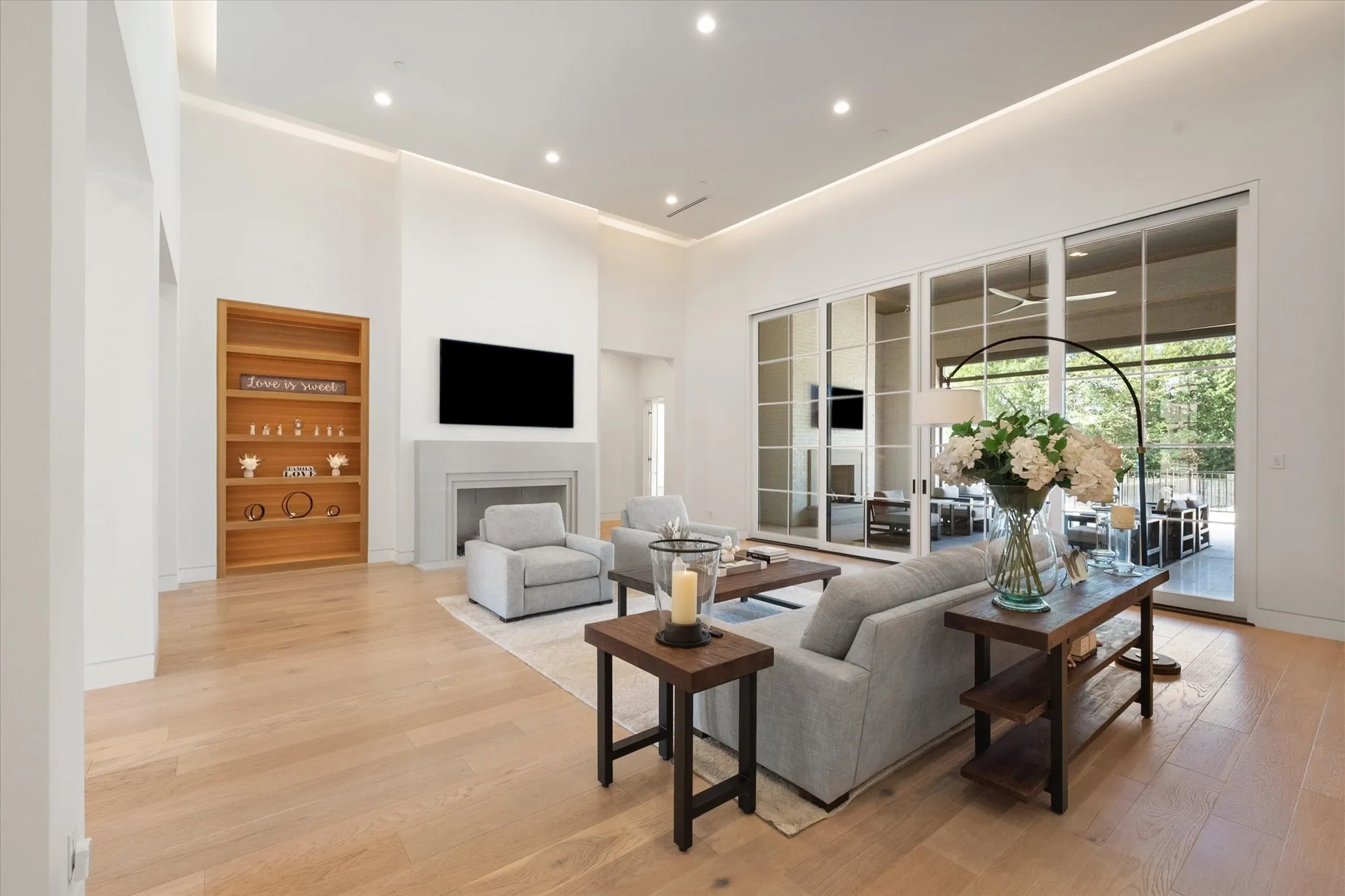 Spacious living area featuring light wood finish flooring. A magnificent Limestone fireplace constructed from a single slab piece. Built-in wood shelving unit