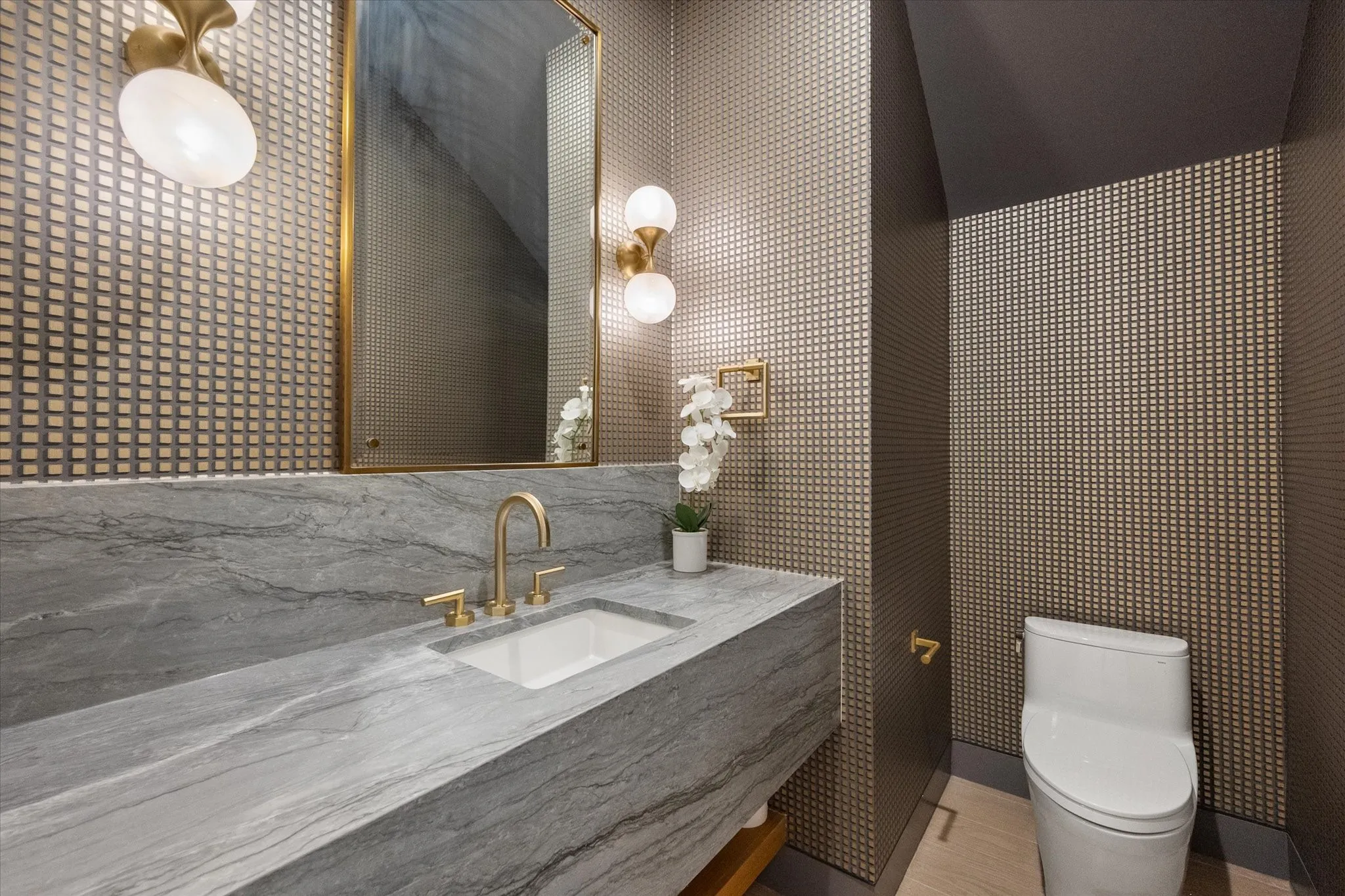 Modern vanity with a gray stone countertop and integrated sink, complemented by a brass faucet