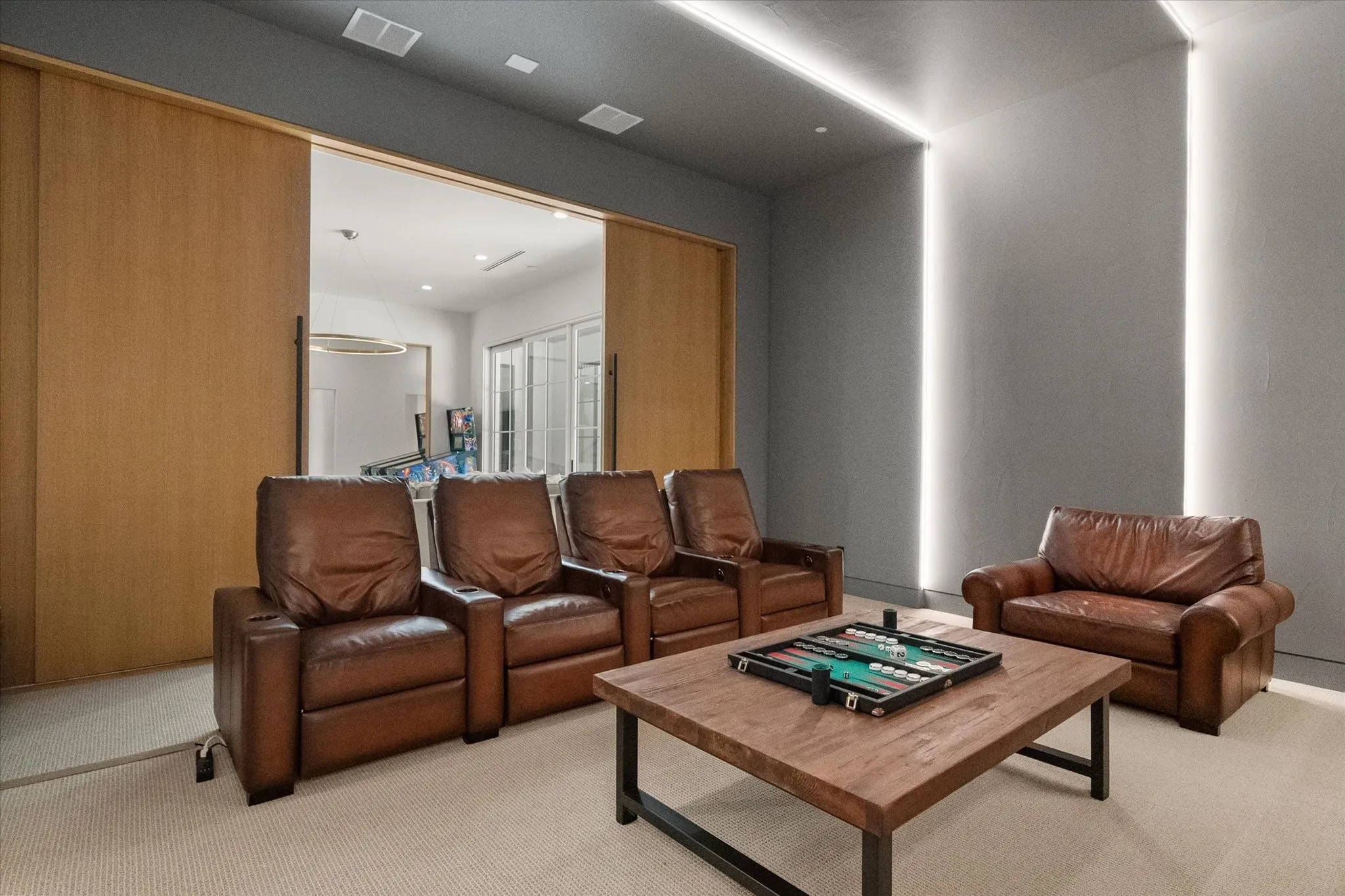 Dedicated media room featuring recessed ceiling lighting, vertical wall lighting, and wood finish sliding doors